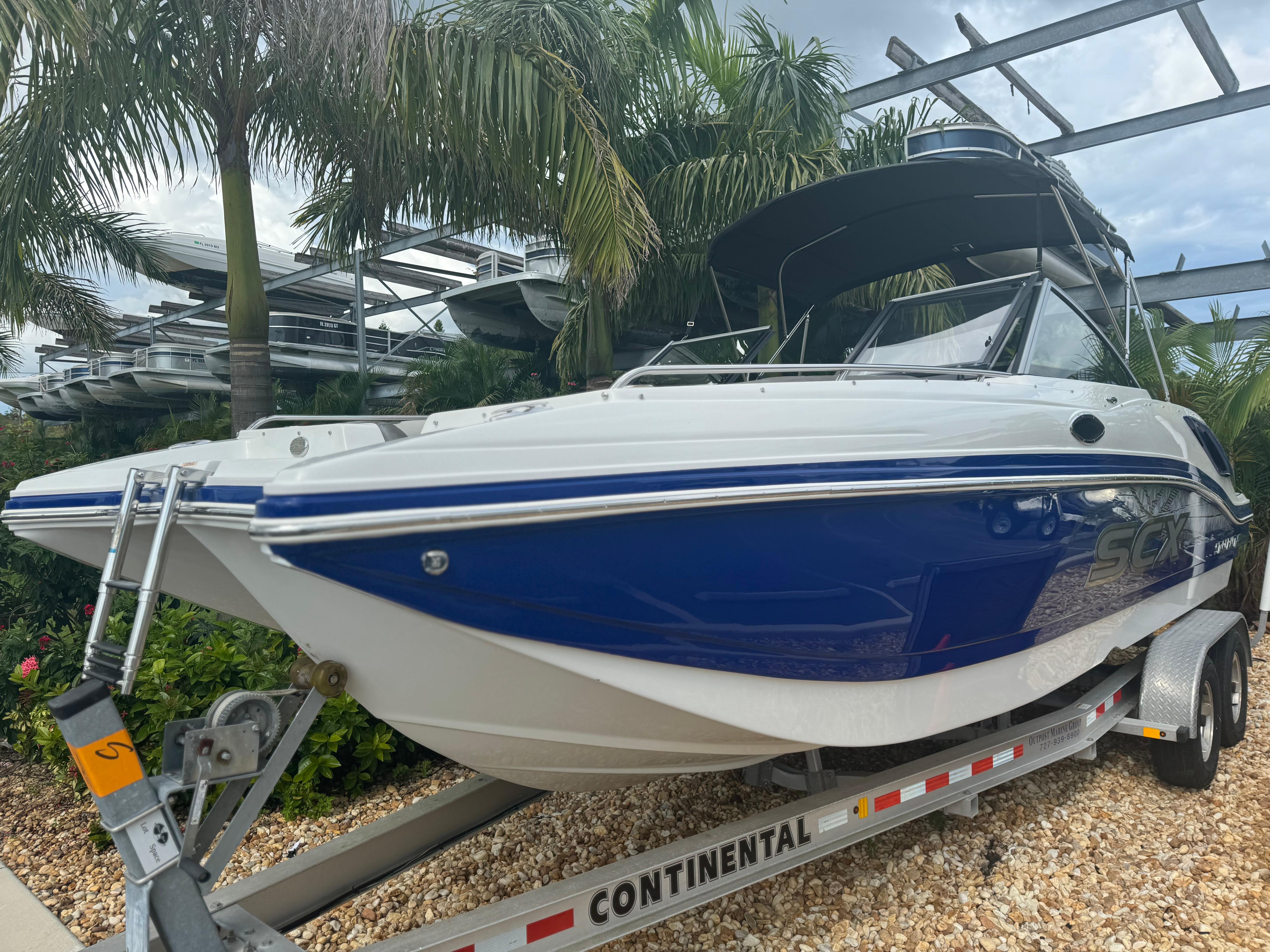 2017 Starcraft 230 OB SCX EXT boat on trailer, surrounded by palm trees.