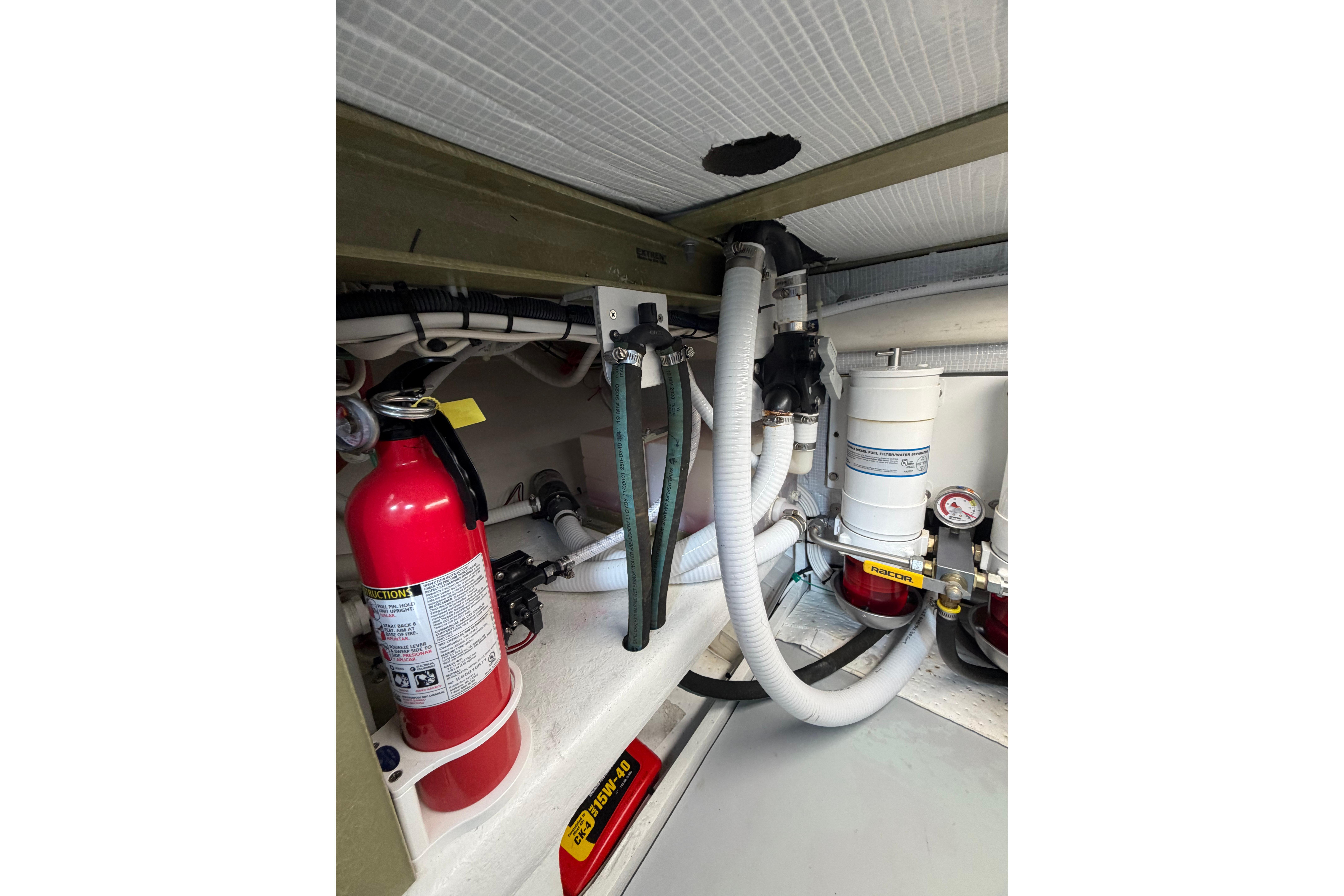 Engine compartment of 2018 H&H Marine Osmond Beal with fire extinguisher and hoses.