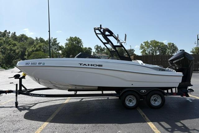 2024 Tahoe T21 boat on trailer, parked outdoors, featuring sleek white design and Mercury outboard motor.
