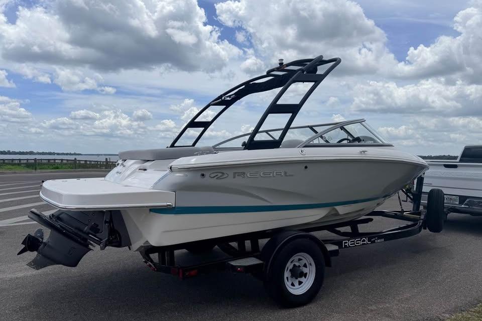 2019 Regal 1900 ES Bowrider on trailer, parked near a scenic lake under cloudy skies.