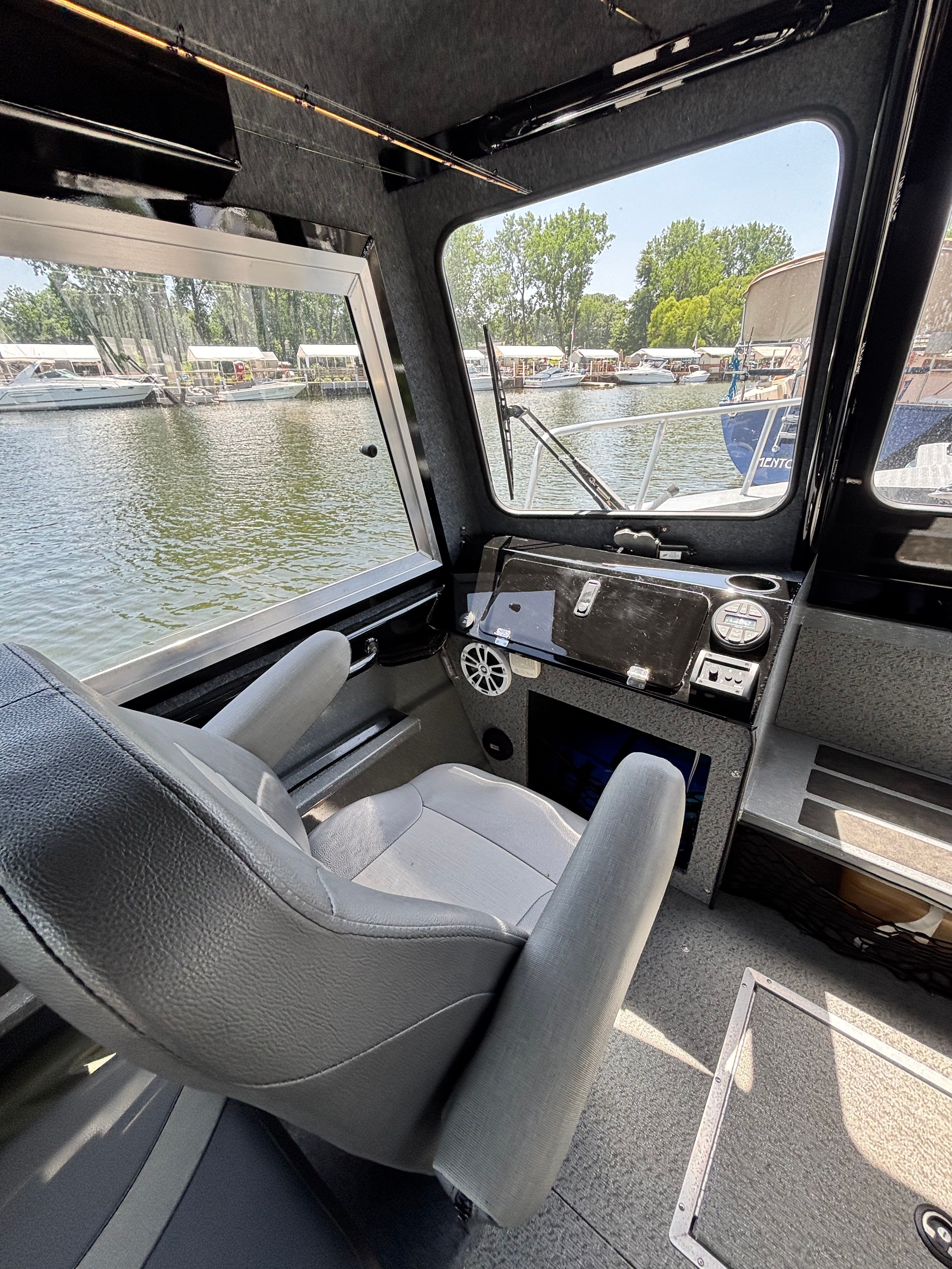 Interior of a Spartan 240 Maximus boat with a gray seat and view of the marina.