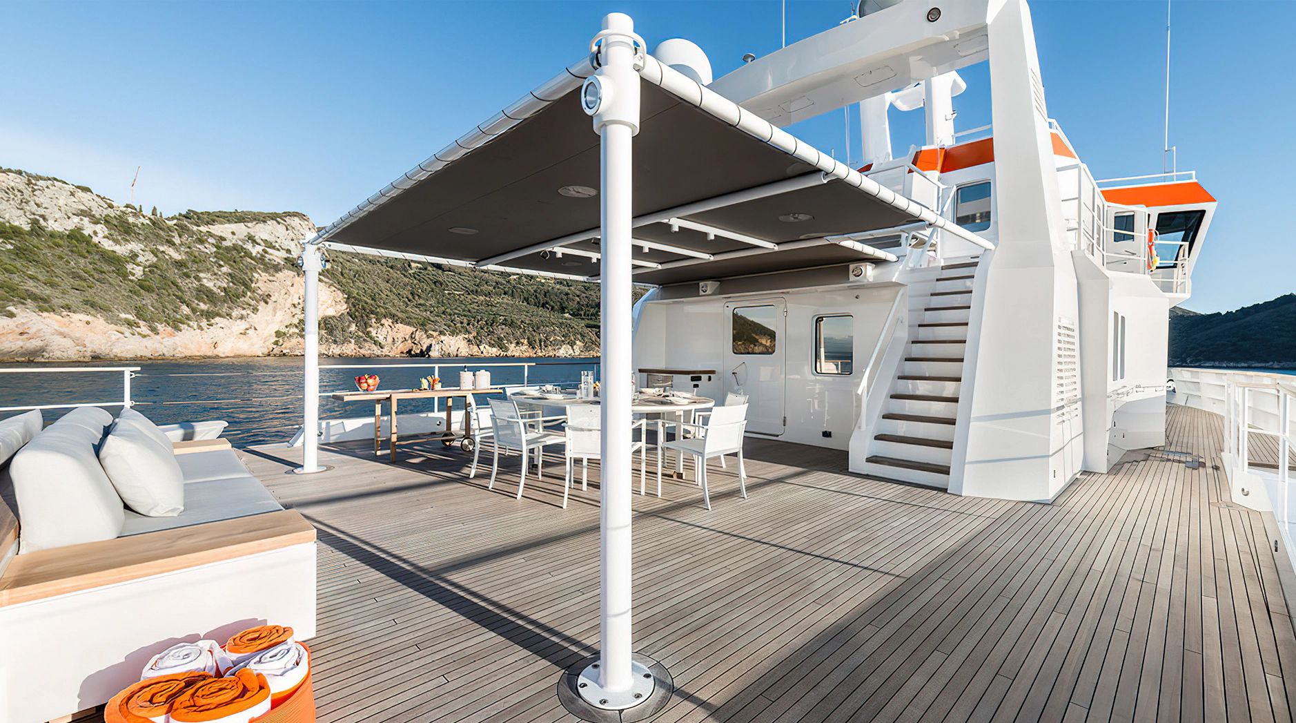 The deck of the Ocean King Explorer 130 features luxurious seating and a dining area overlooking the water.