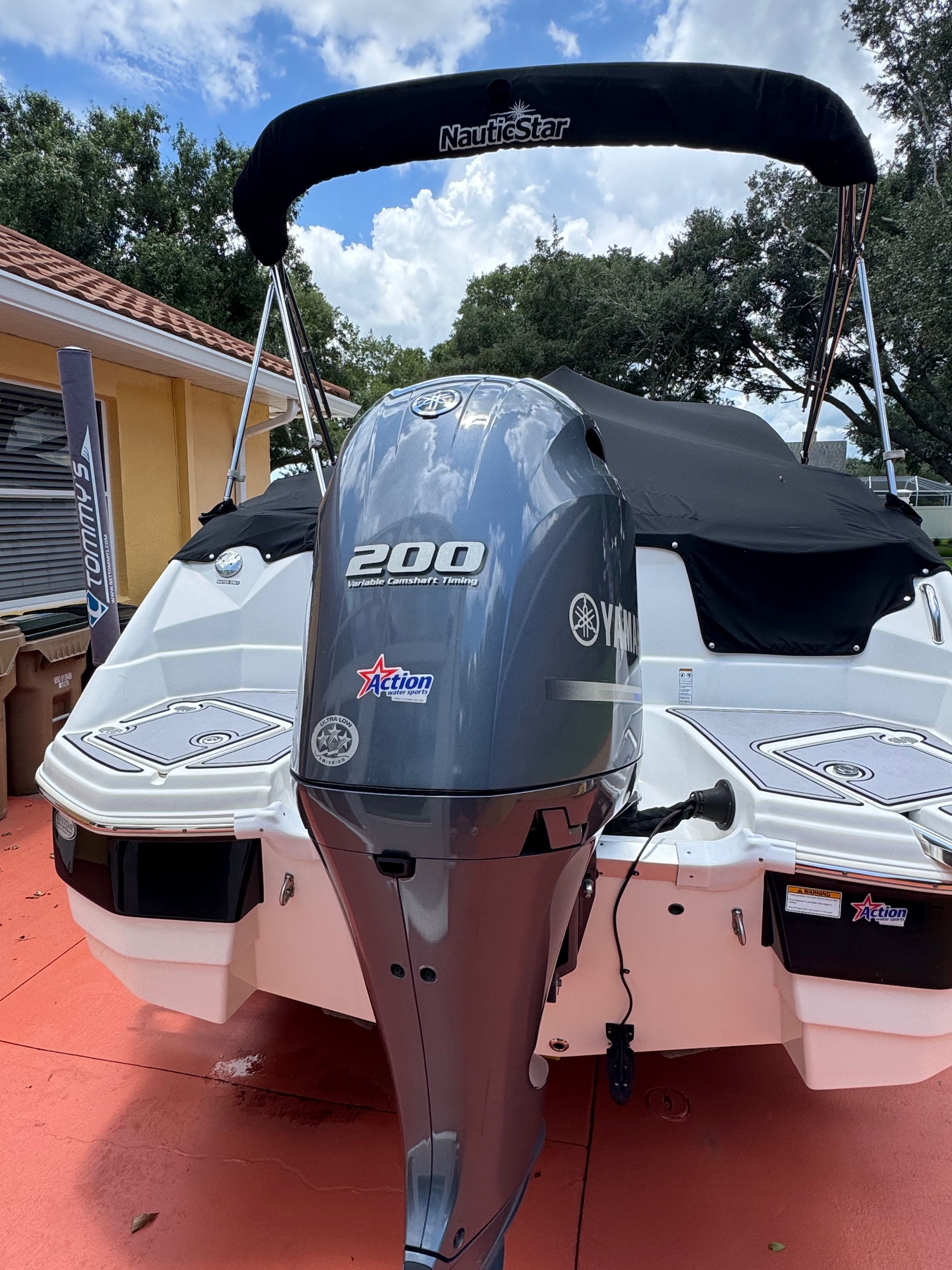 2022 NauticStar 243 DC with Yamaha 200 HP outboard motor, black bimini top, and cover.
