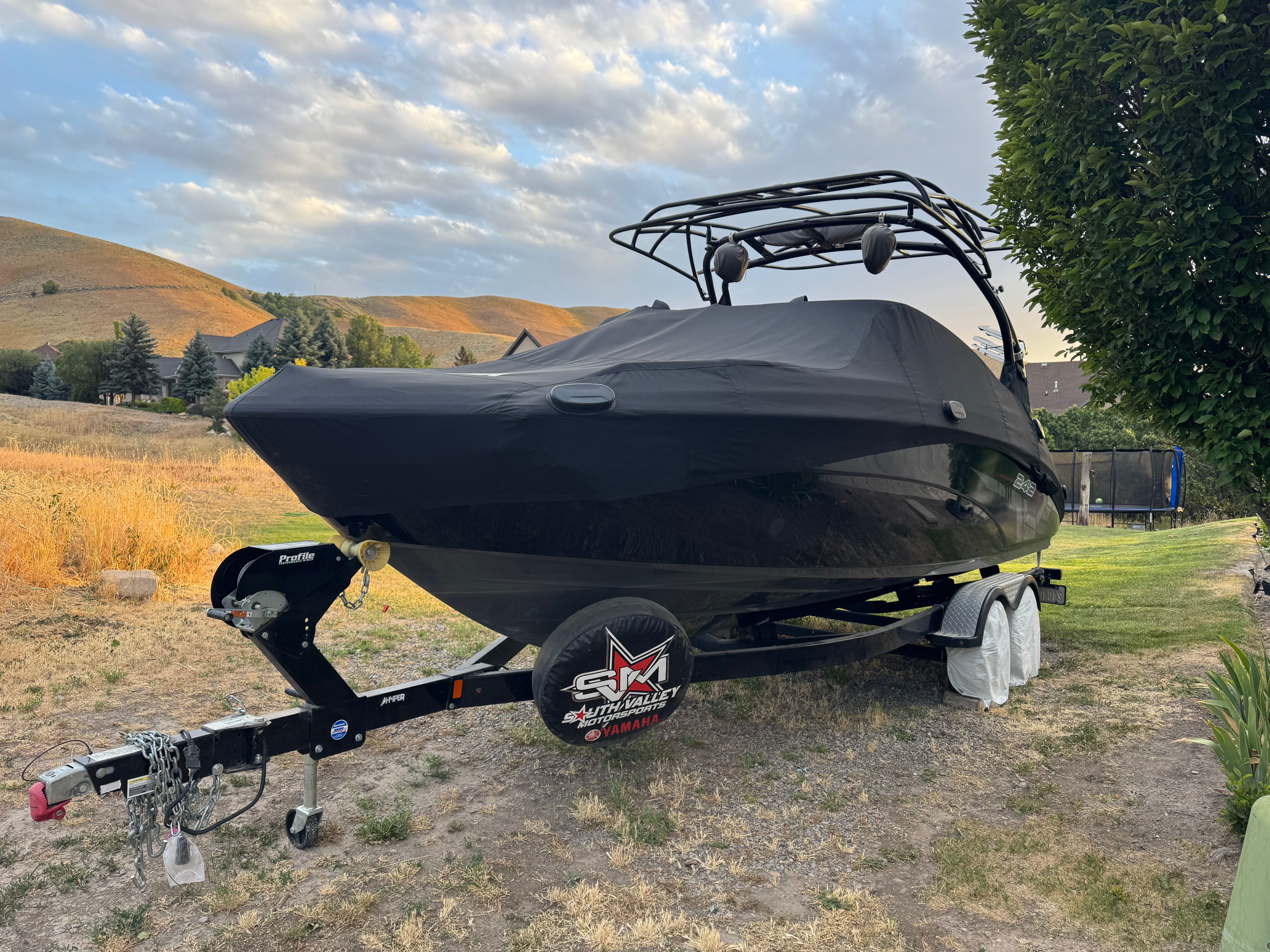 A 2017 Yamaha 242X E-Series boat on a trailer in a rural setting.