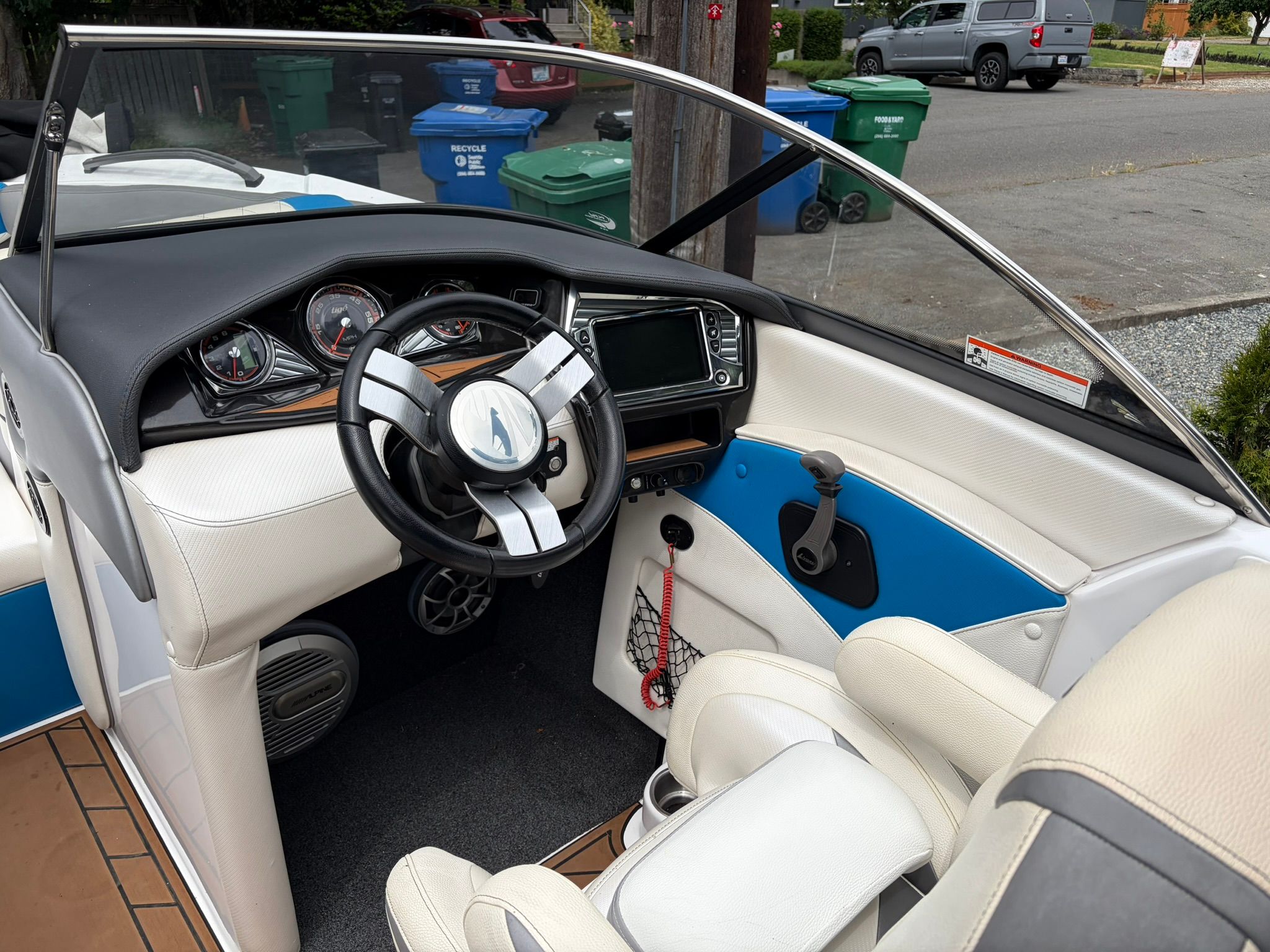 The image shows the cockpit of a 2016 Tigé RZ2 boat with white and blue seats and a modern dashboard.