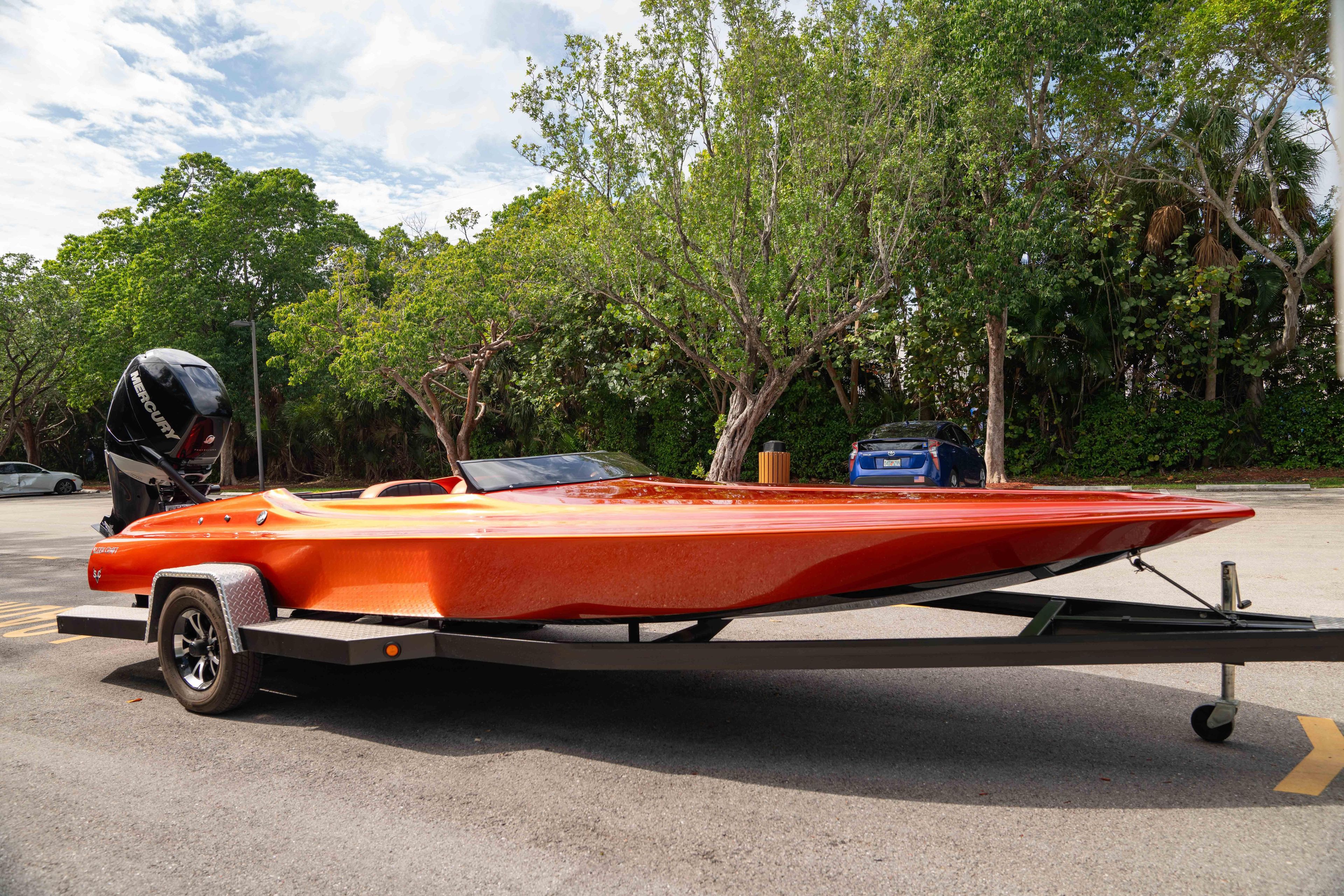 1984 Sleekcraft Aristocrat 20 boat on trailer, vibrant orange, parked outdoors.