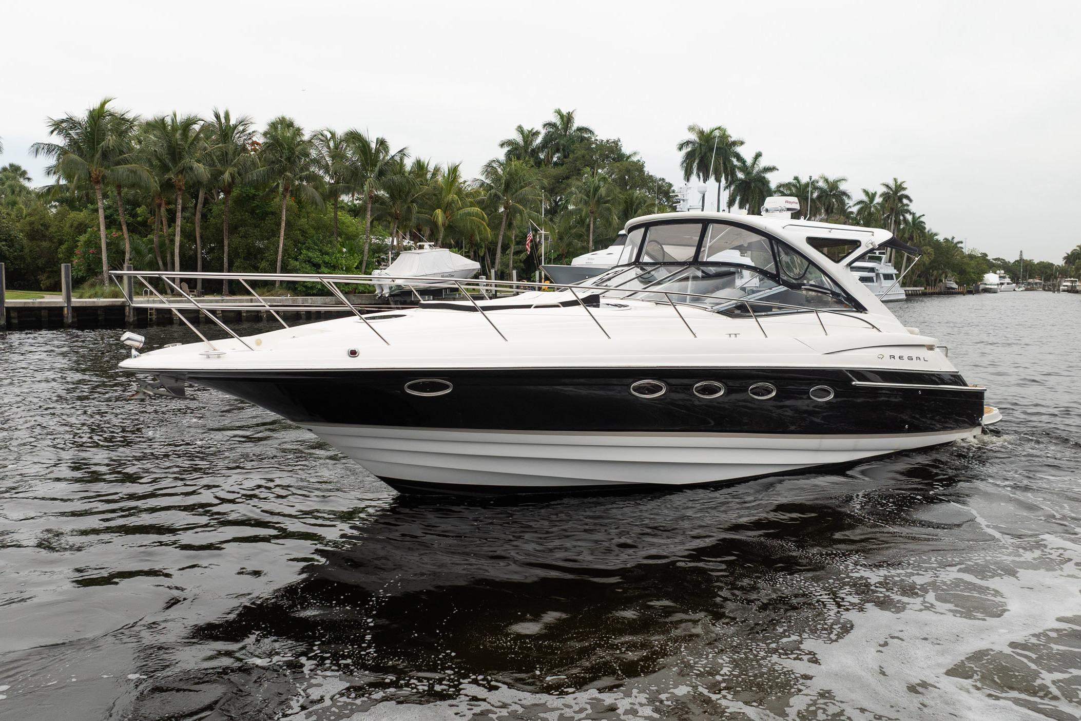 2008 Regal Commodore 4460 yacht cruising on a scenic waterway with lush palm trees.