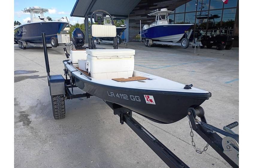 2013 Pelican Ambush boat on trailer, parked at a marina with other boats.