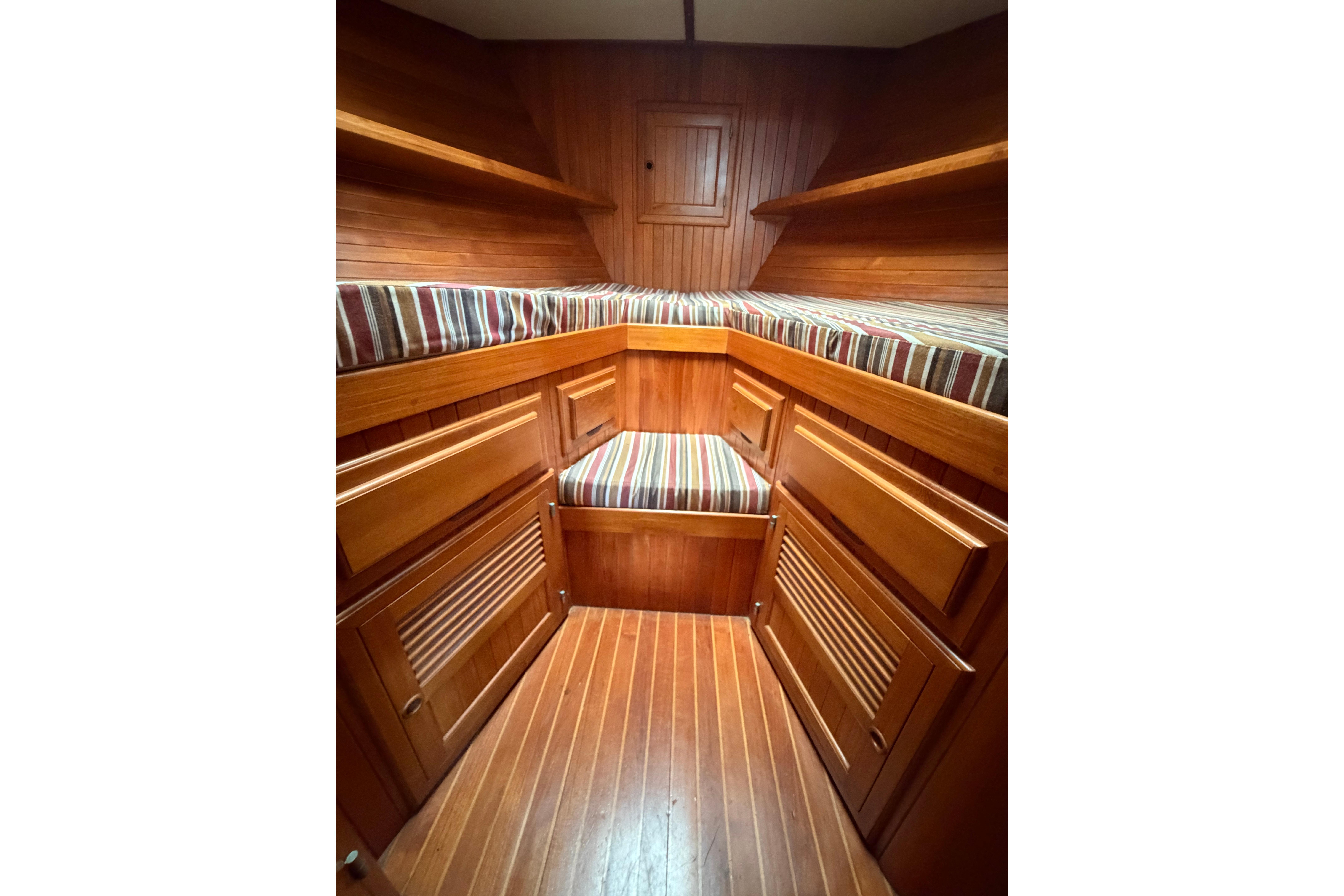 Cozy wooden cabin interior of 1988 Monk 36 boat with striped cushions.