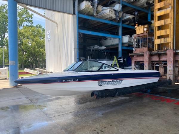 1998 Malibu Response boat in storage facility, side view, white and blue design.