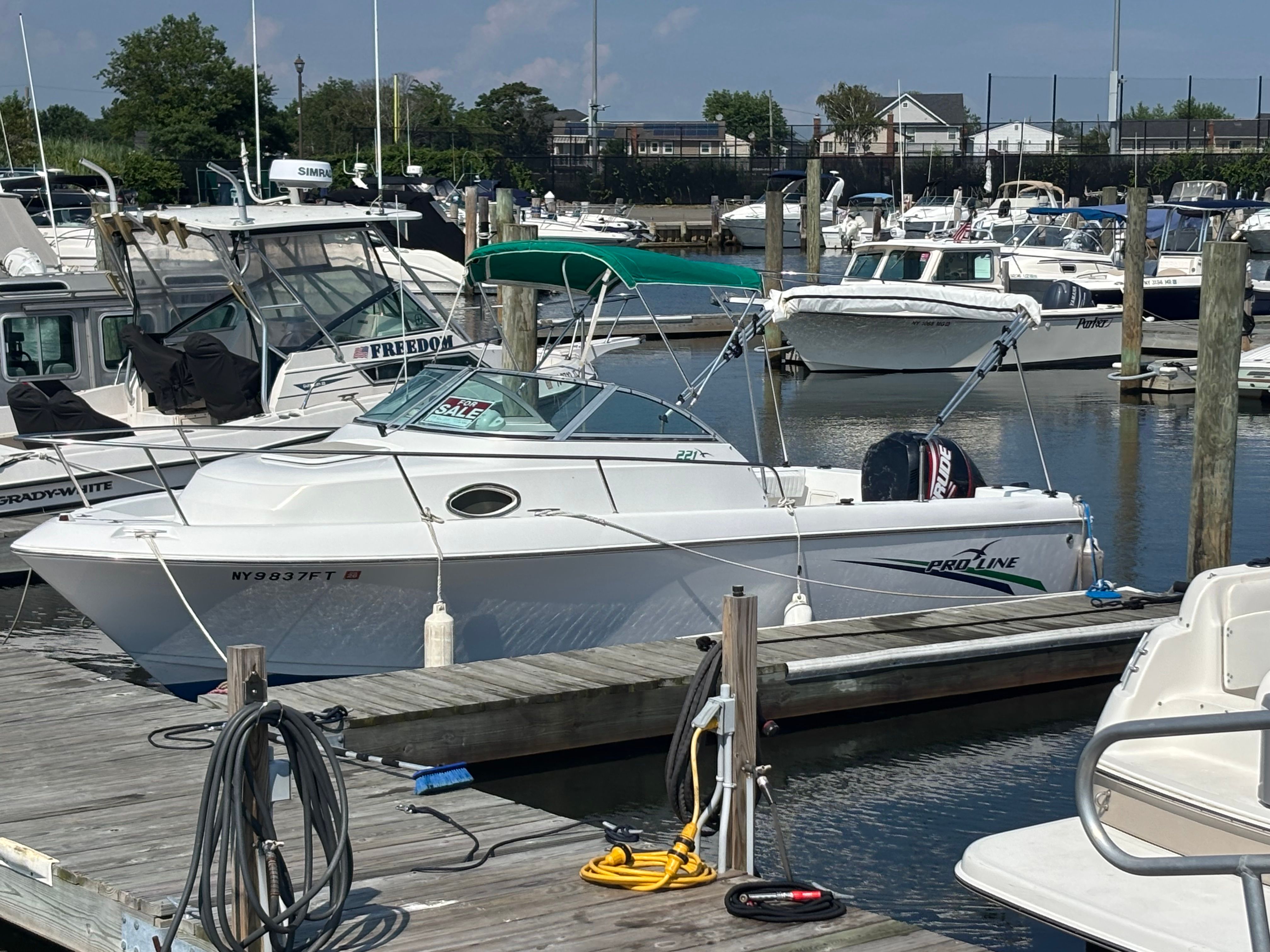 A white 1999 Pro-Line 221 Walk Around boat docked at a marina.