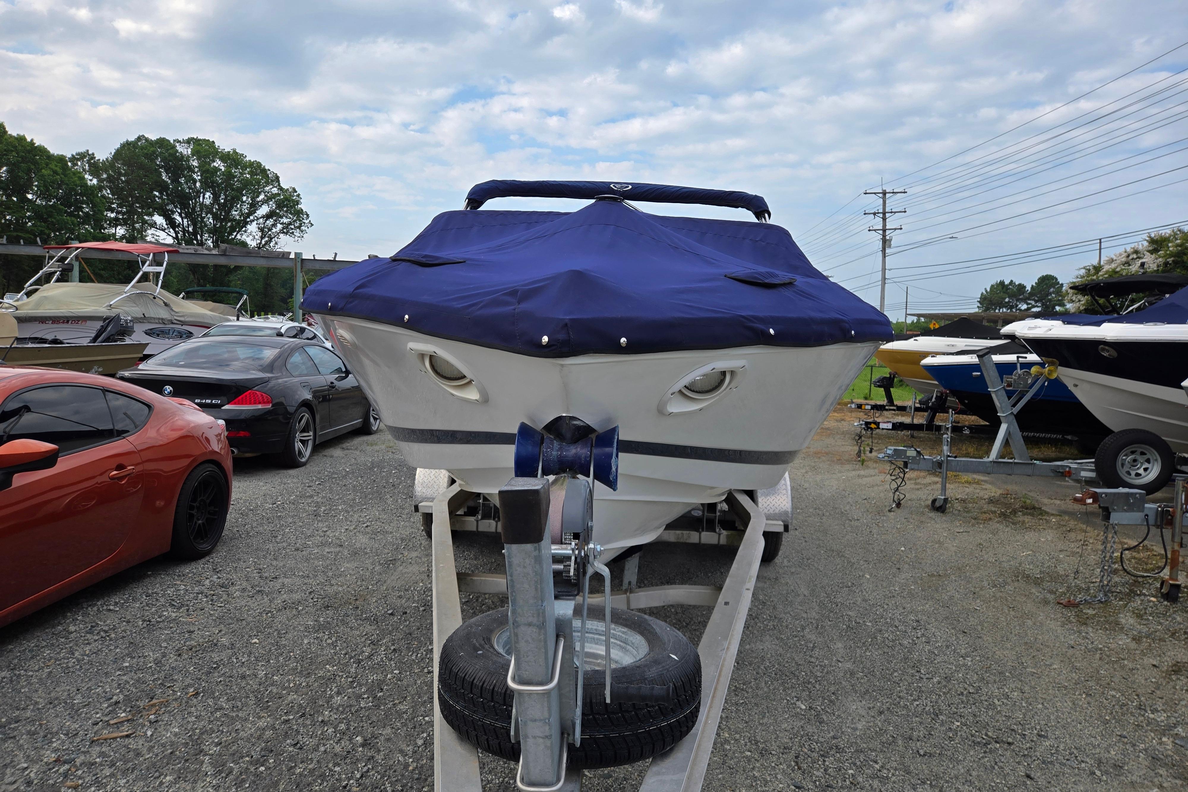 Covered 2000 Cobalt 246 boat on trailer, surrounded by parked cars and other boats.