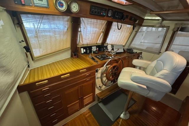 Pilothouse of 1986 Kadey-Krogen 42 yacht with wooden helm and white captain's chair.
