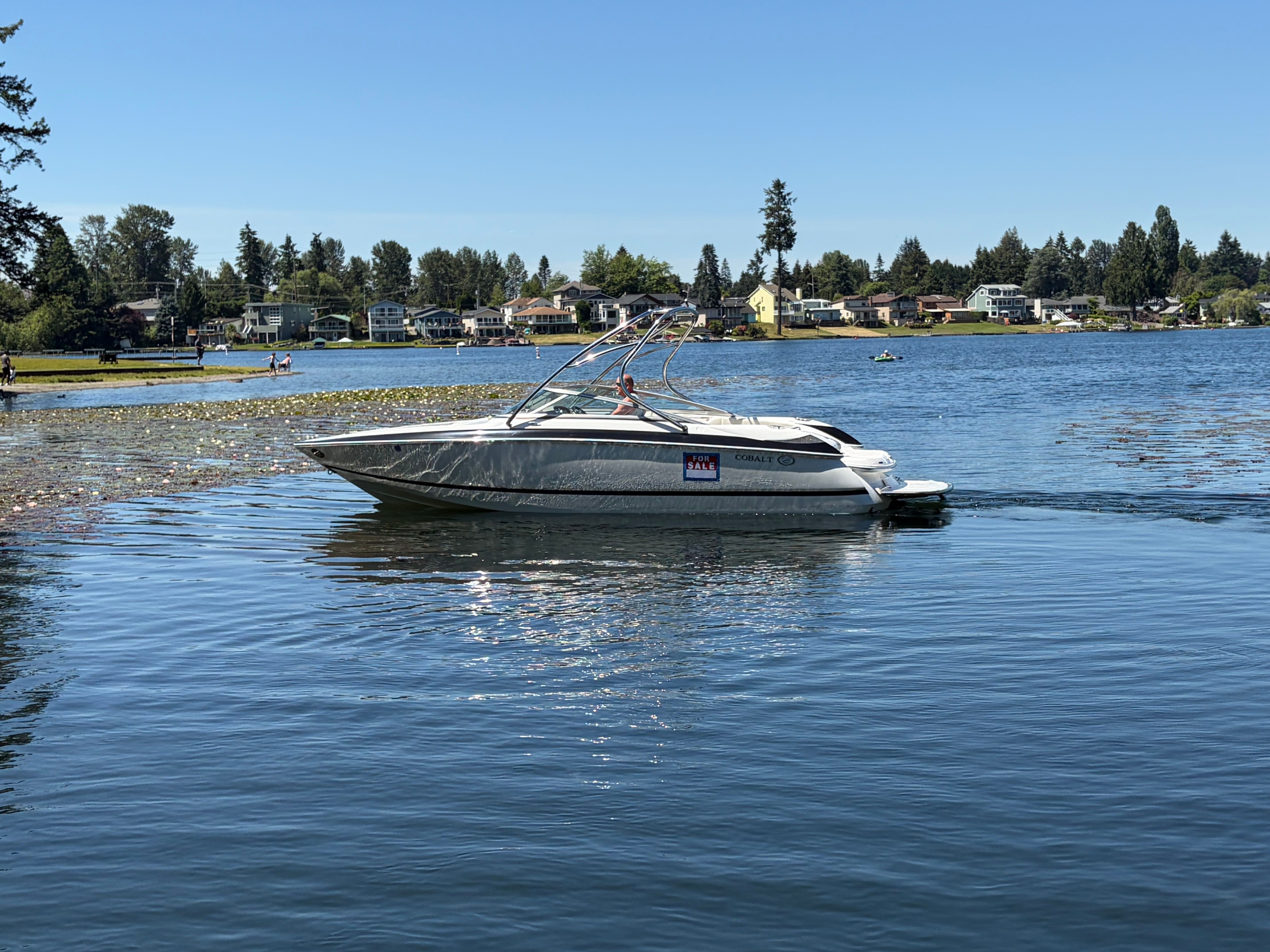 2006 Cobalt 240 boat on a calm lake with 'For Sale' sign.