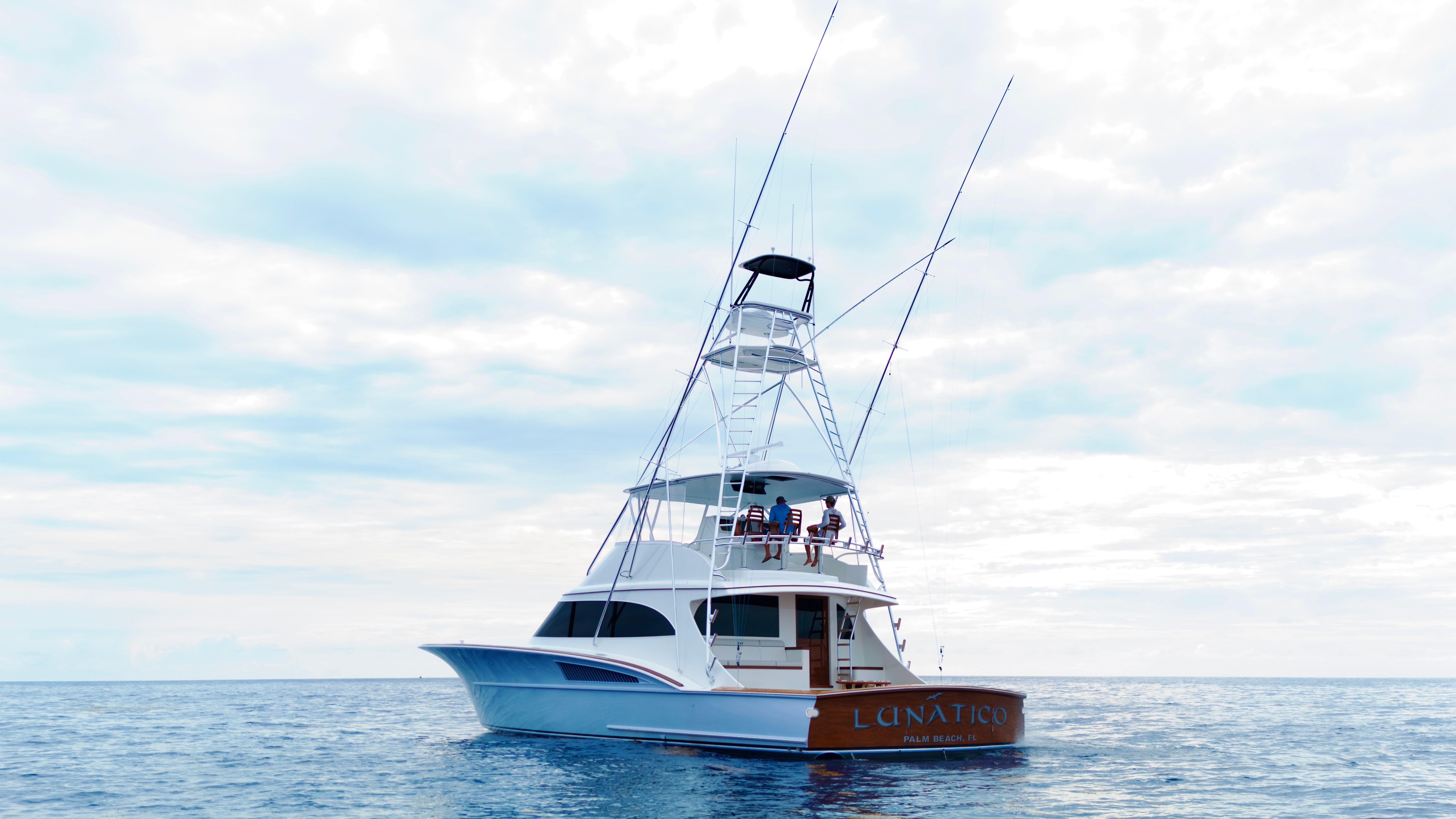 A modern sportfishing boat with a tall tower on calm water.
