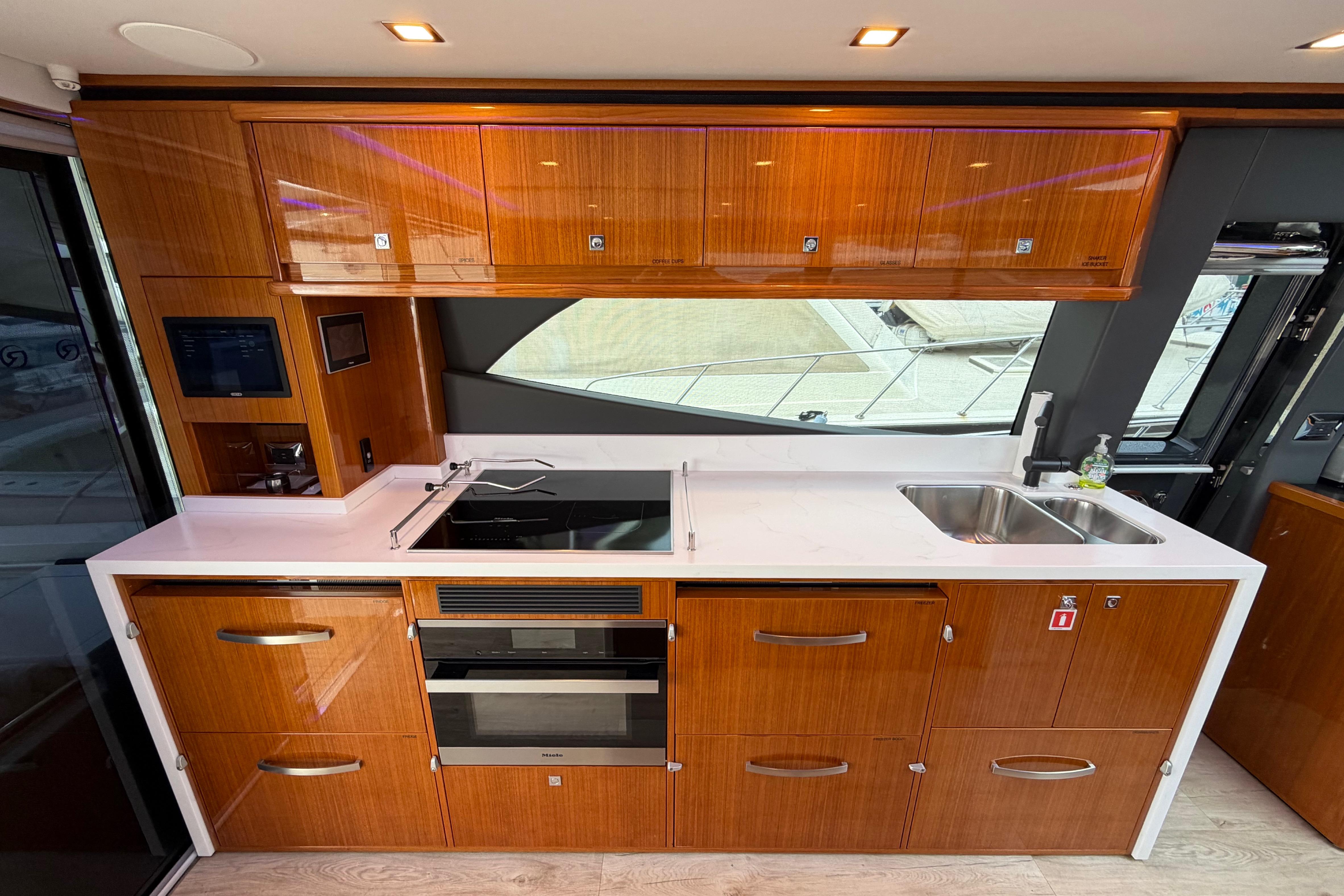 Luxurious kitchen interior of 2023 Riviera 645 SUV yacht with modern appliances and sleek cabinetry.