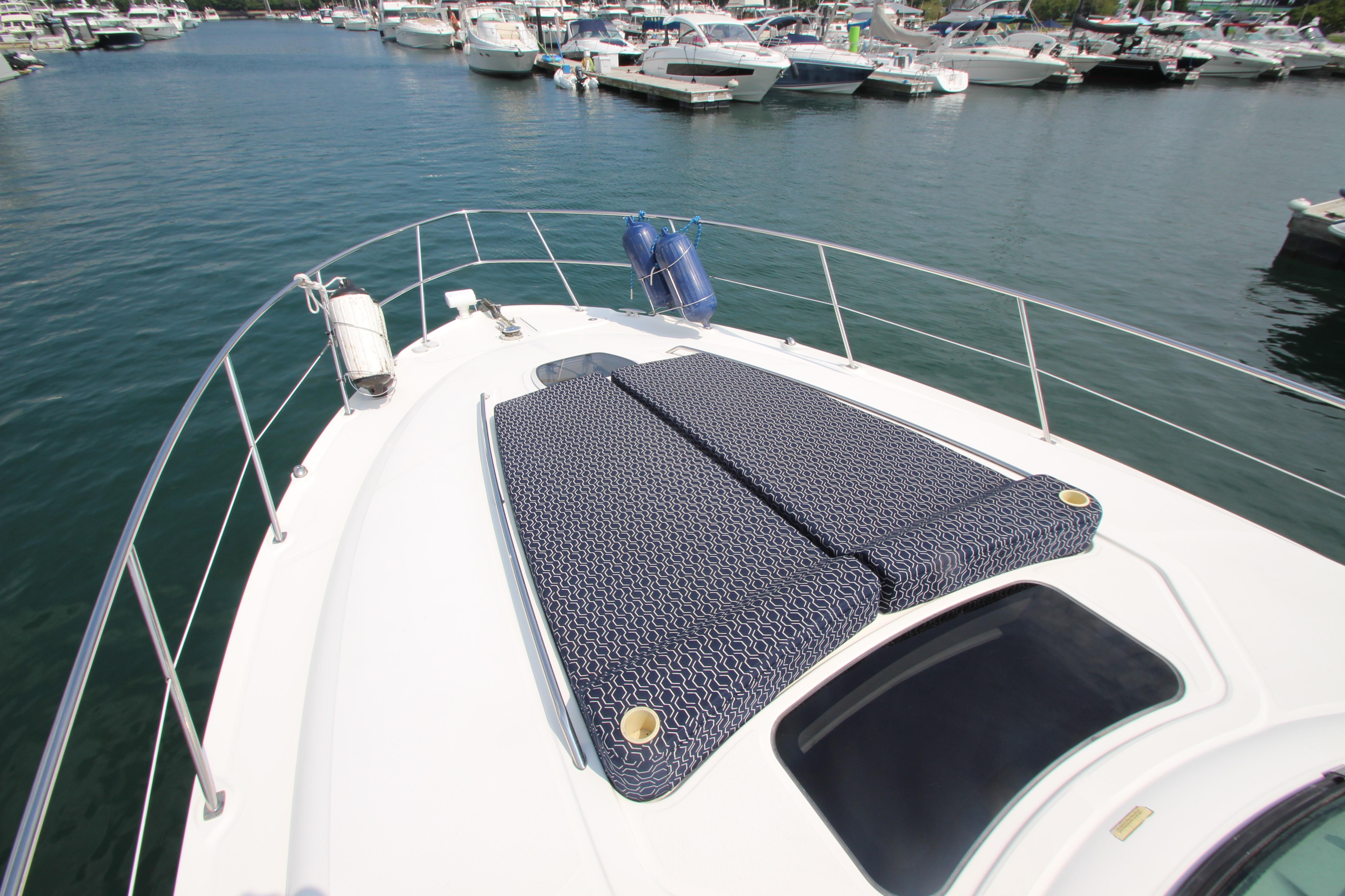 2004 Sea Ray 40 Sundancer yacht with sun pads, docked in a marina.
