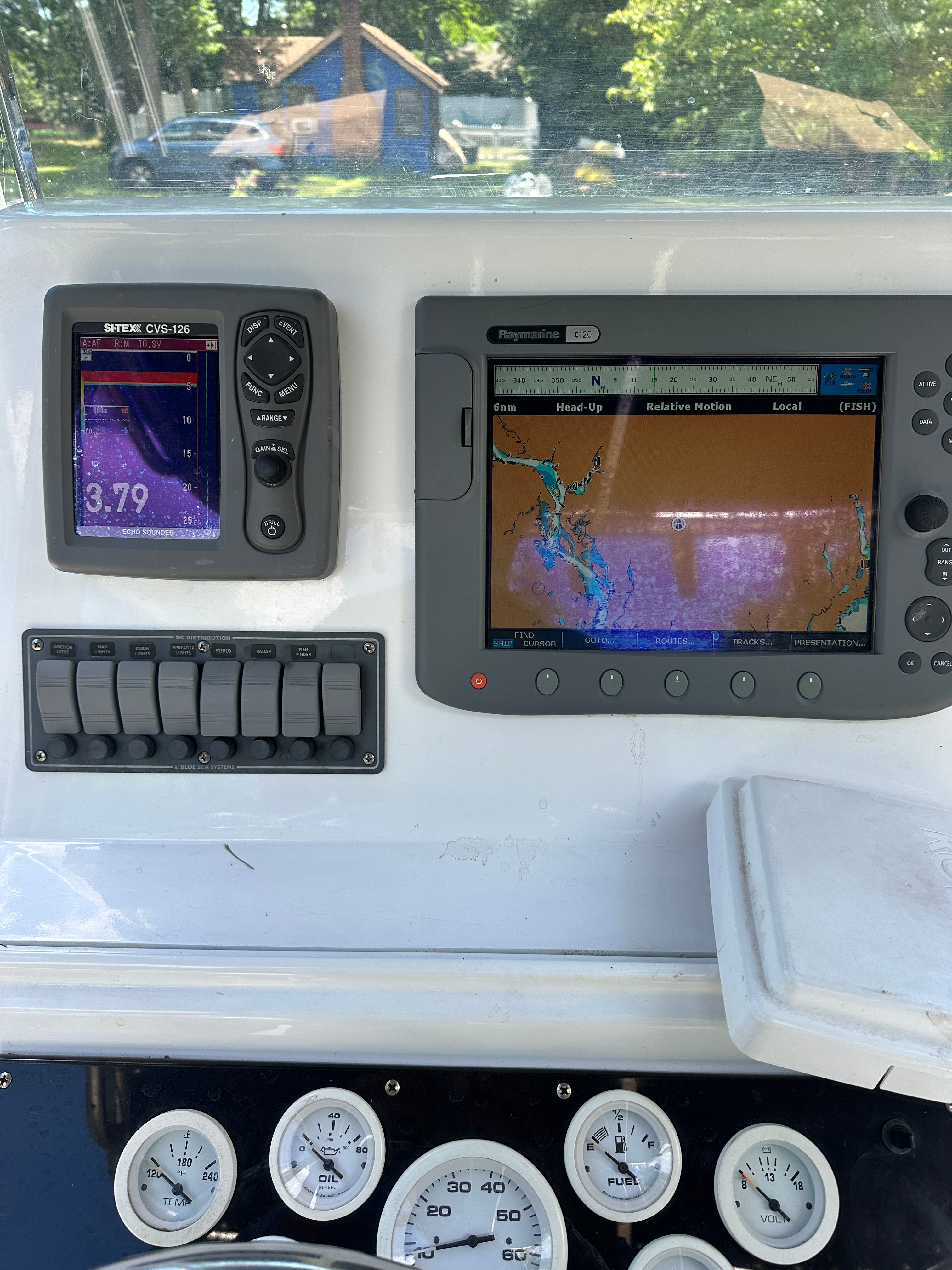 The image shows a boat's dashboard with navigation equipment and gauges.