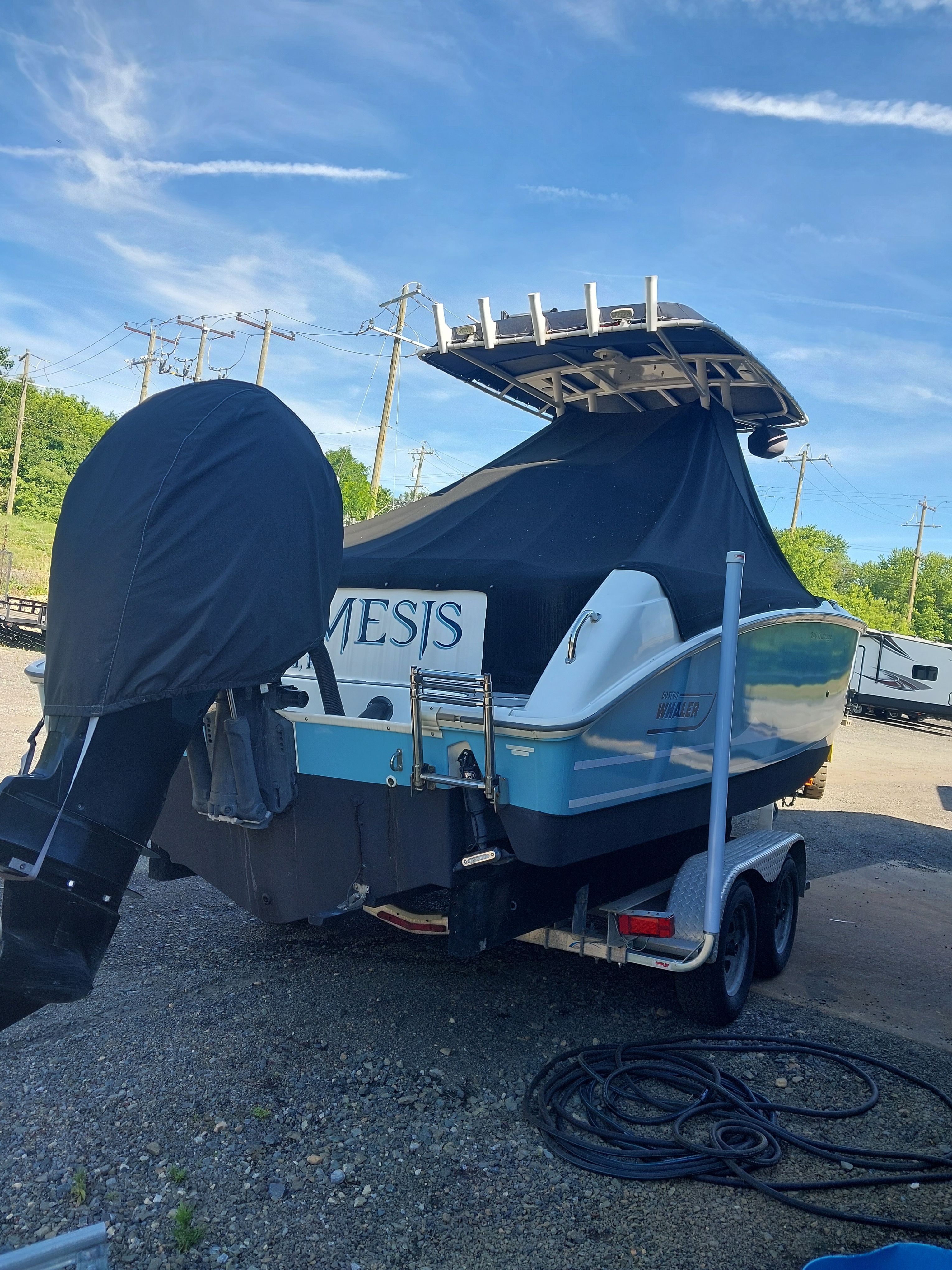 A 2005 Boston Whaler 240 Outrage on a trailer. The motor is covered.