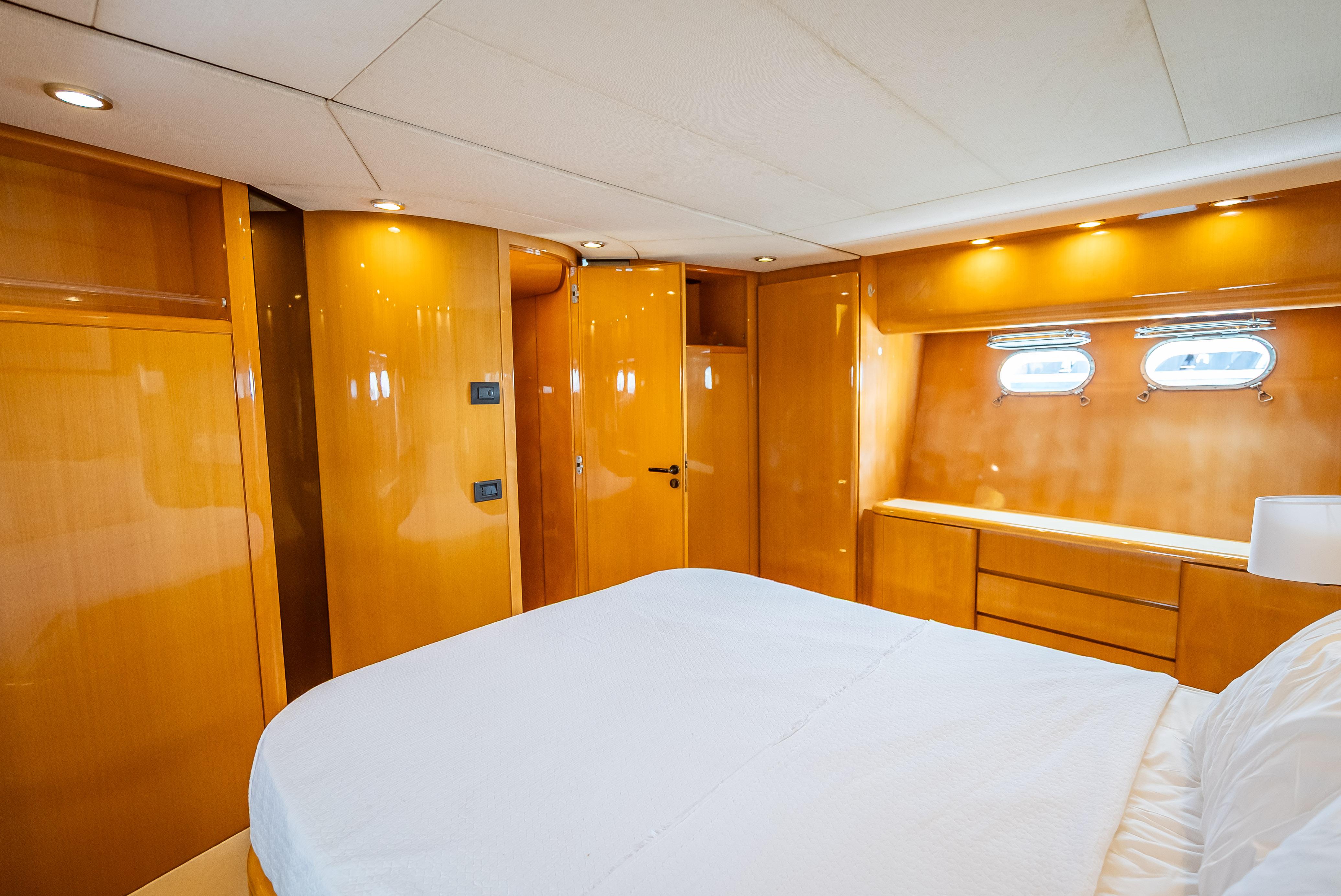 Luxurious cabin interior of 1995 Sanlorenzo 62 yacht with wood paneling and porthole windows.