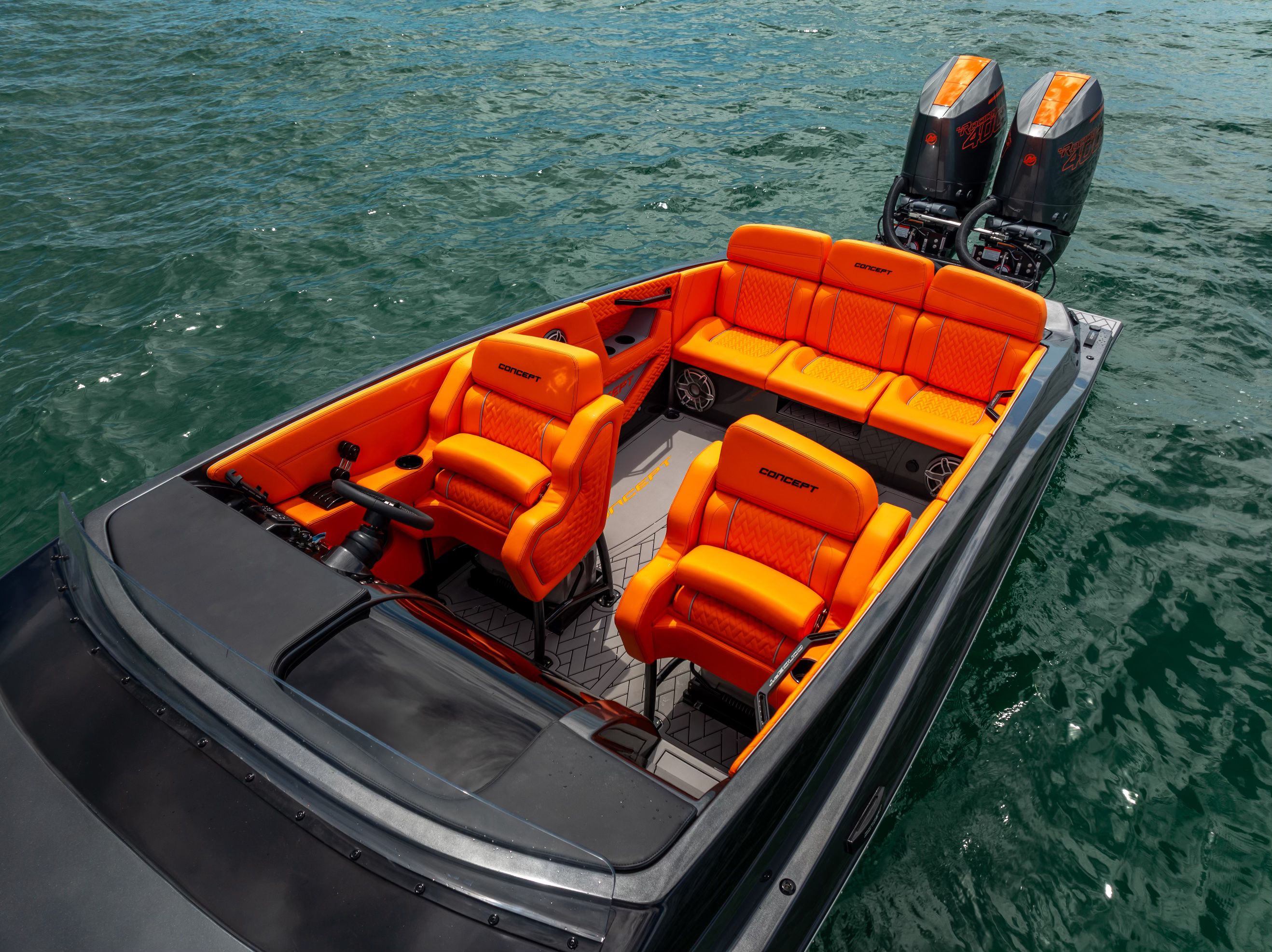 A modern sport boat with bright orange seats and two outboard engines on the water.