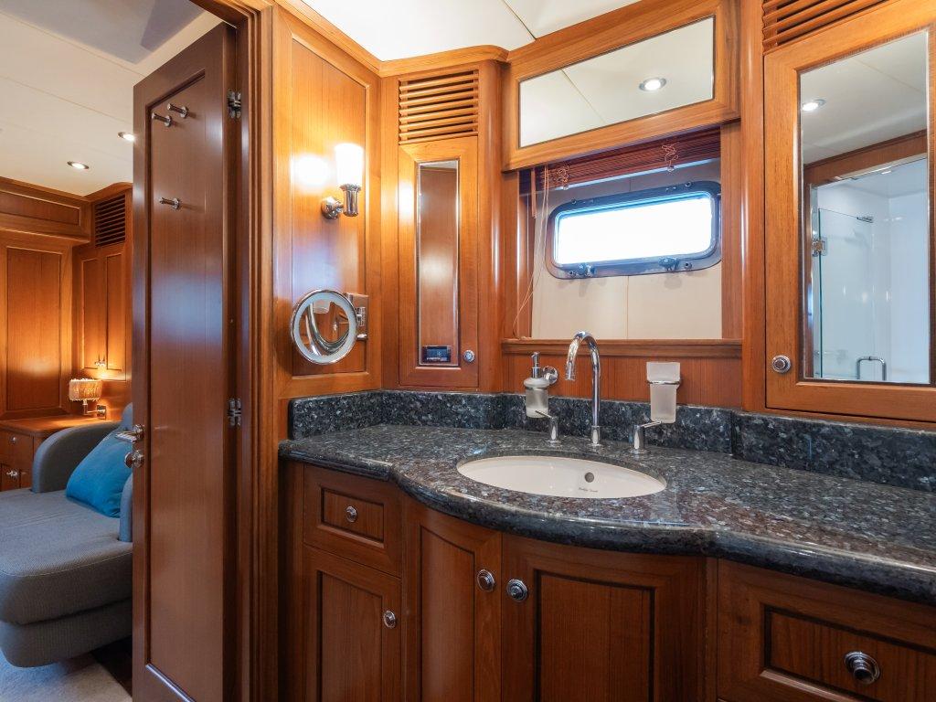 Luxurious bathroom in 2008 Trader 64 Sunliner yacht with wood cabinetry and granite countertop.