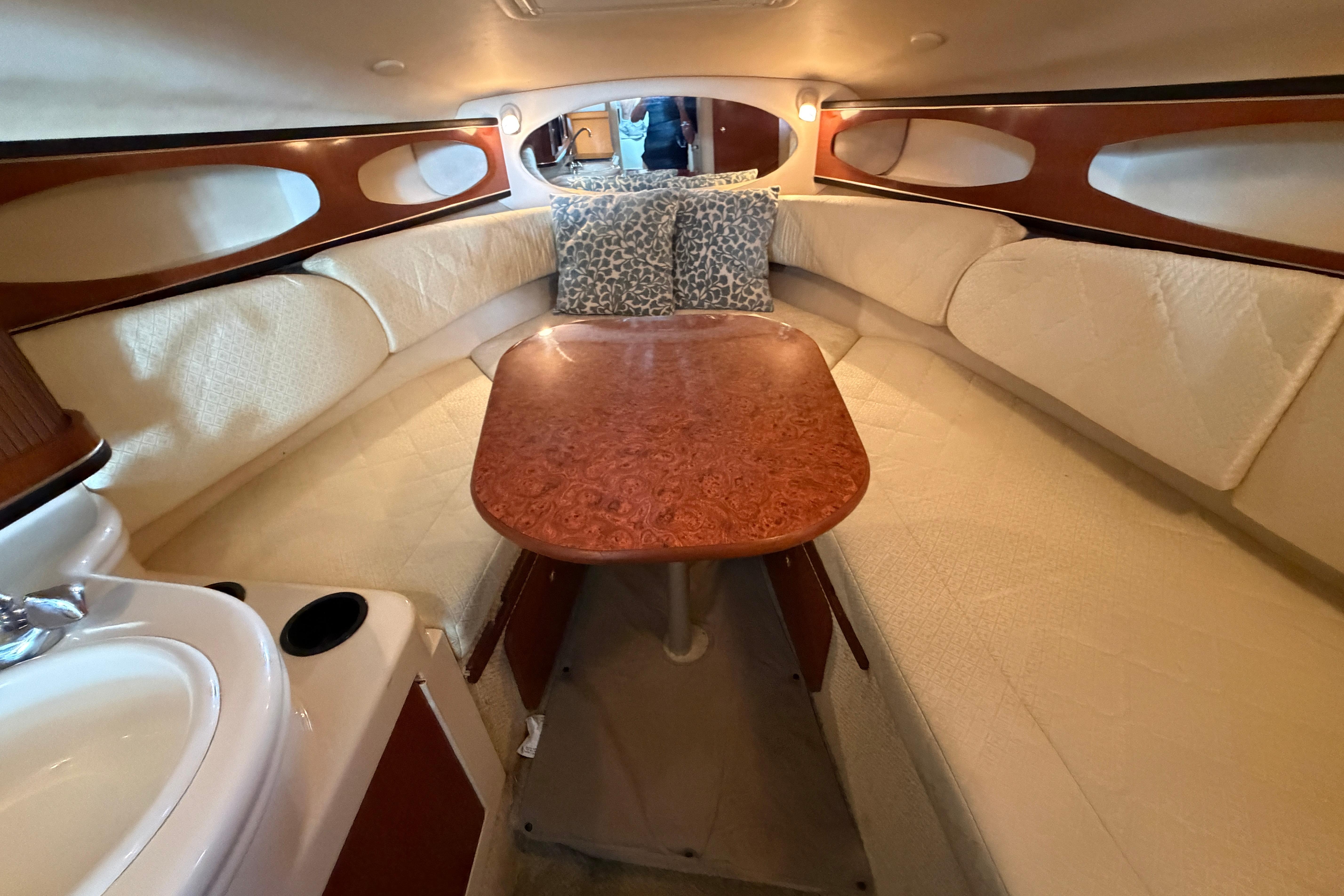 Interior of 2004 Sea Ray Sundancer 260, featuring cozy seating and elegant wood table.