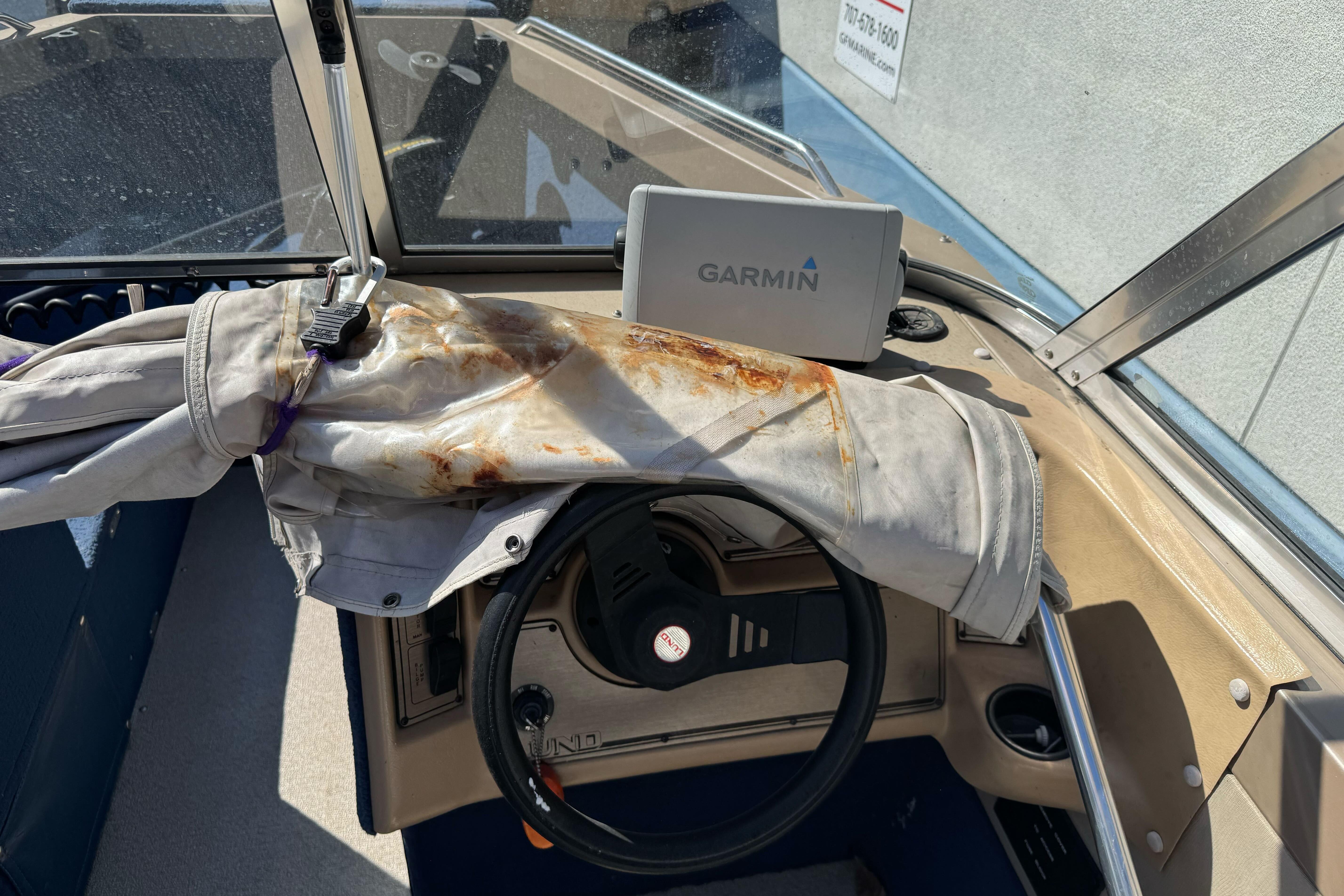 1998 Lund 1700 Pro Sport boat interior with Garmin GPS and weathered steering wheel cover.