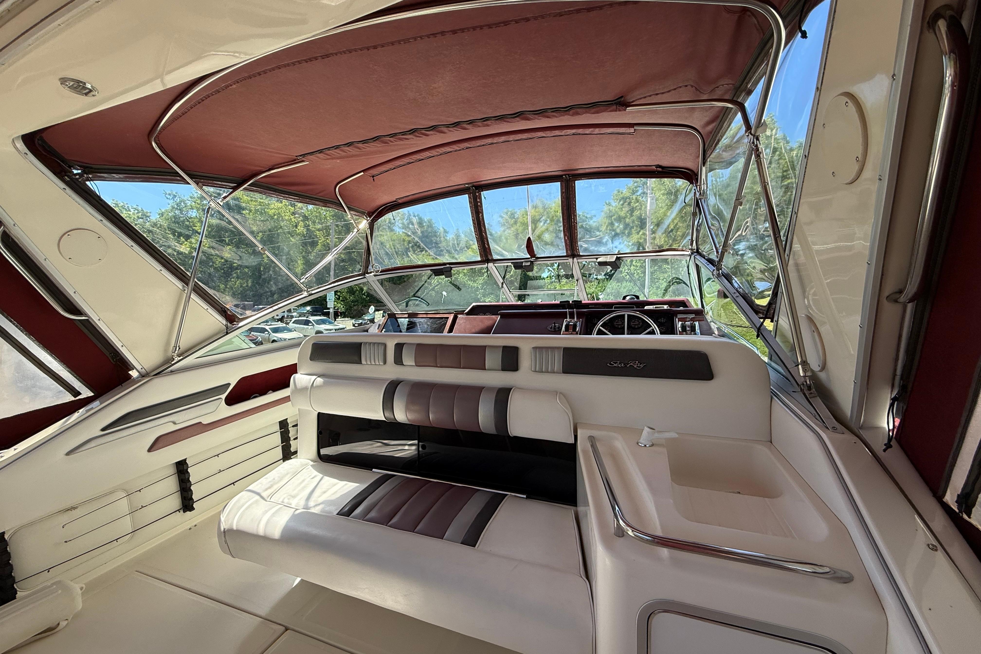 1990 Sea Ray 310 Express Cruiser interior with maroon canopy and seating area.
