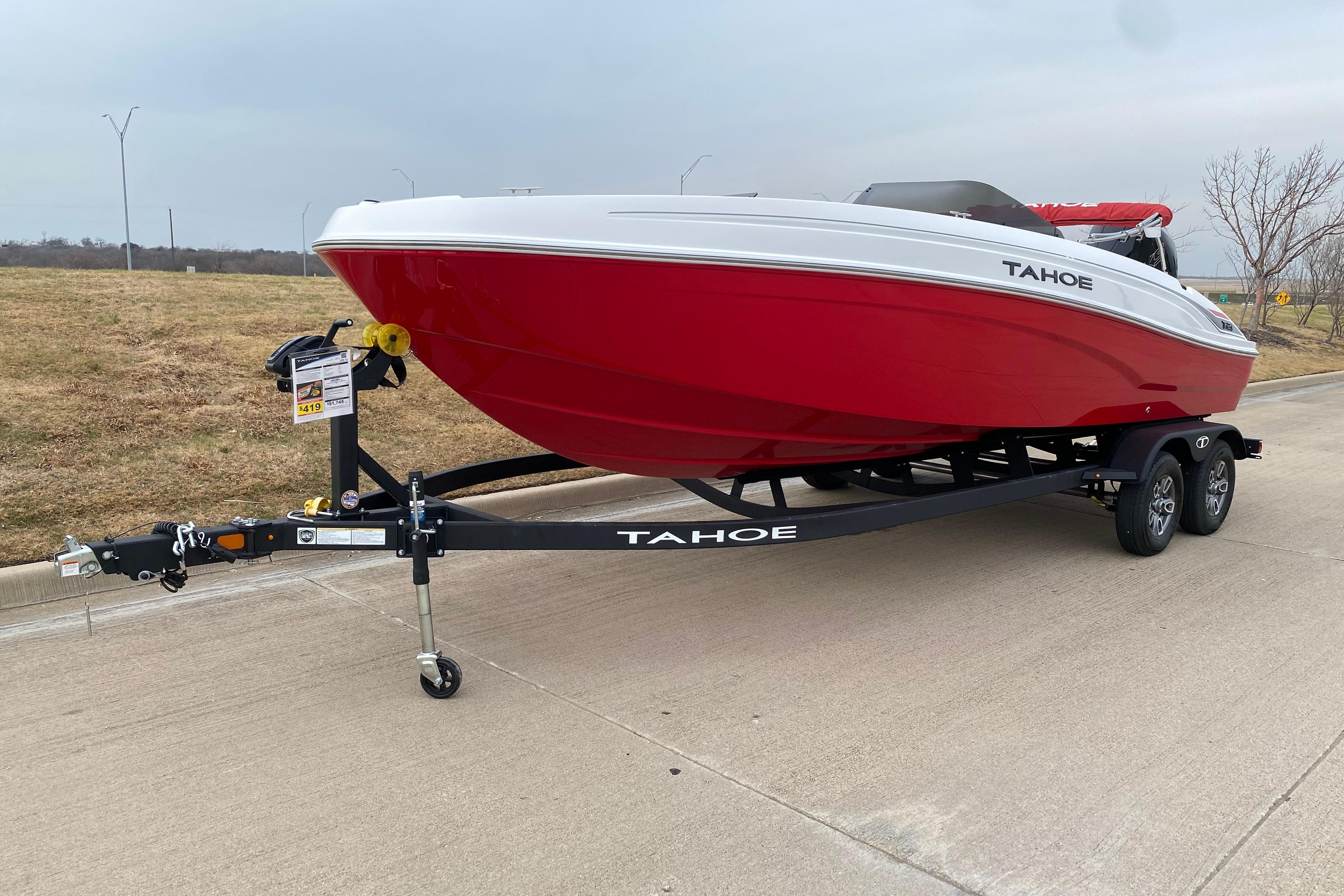 2026 Tahoe T21 boat in red and white on a trailer, parked on a concrete surface.