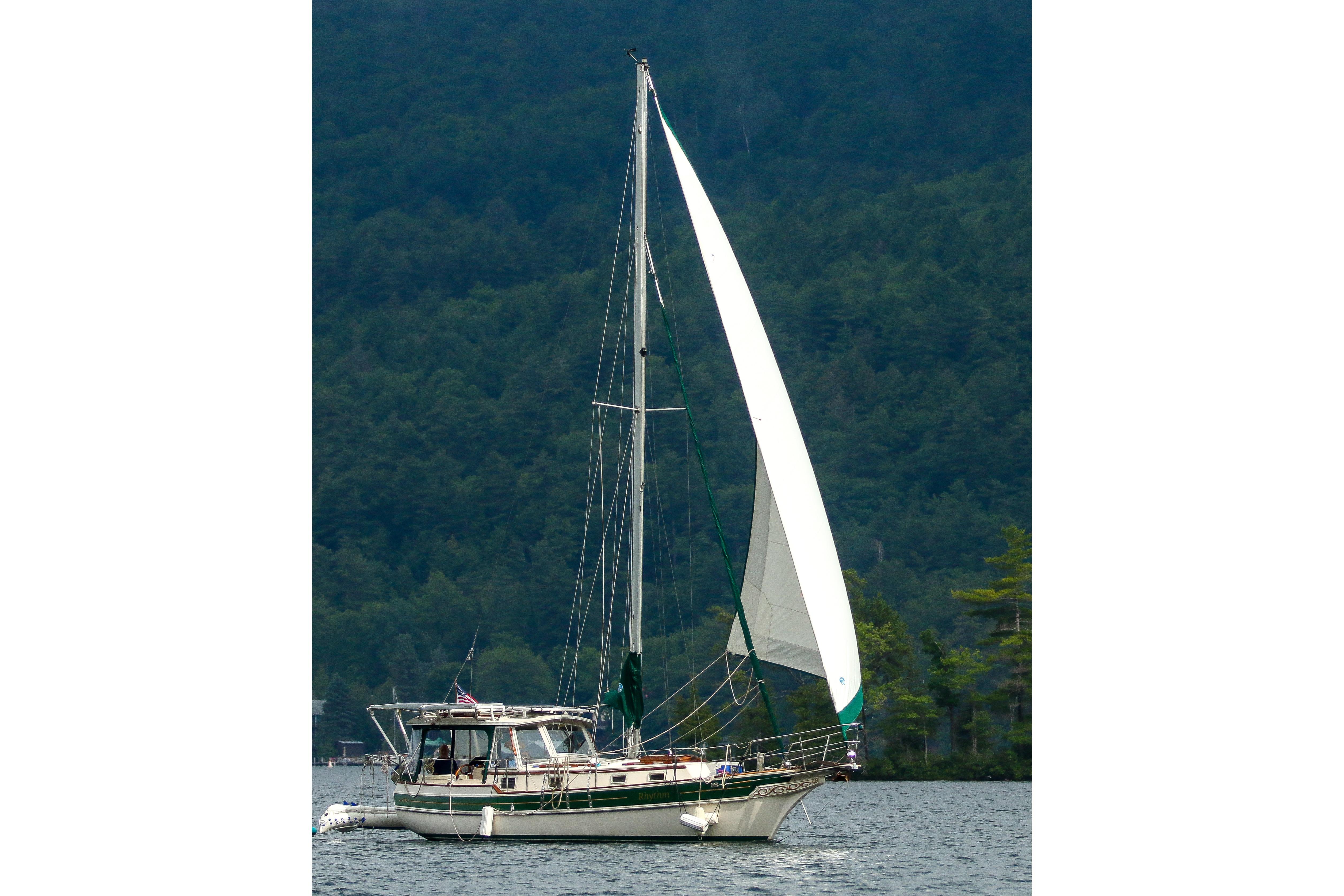 Sailing yacht Gozzard 31 from 1991 on a serene lake with forested backdrop.