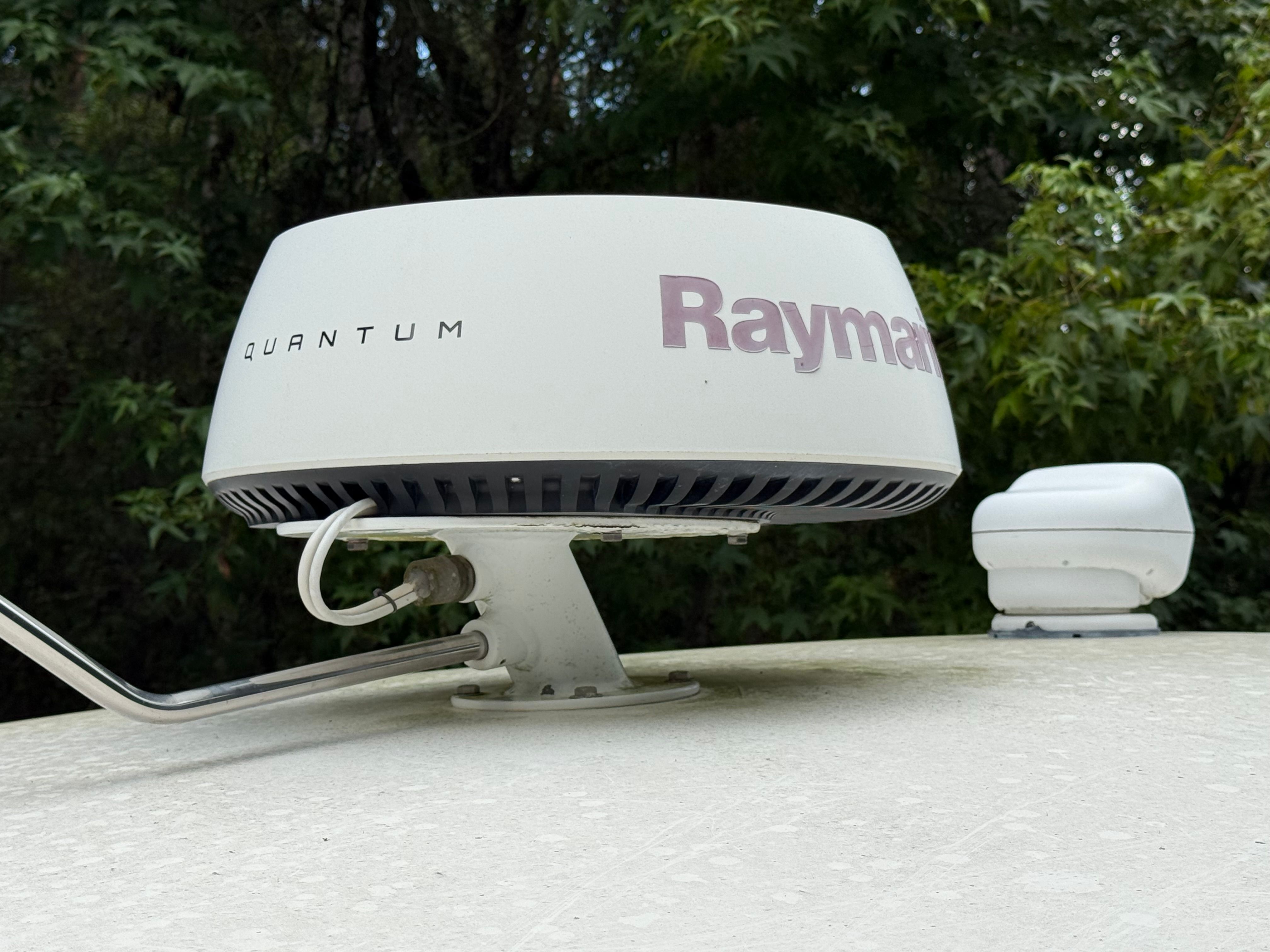 A Raymarine Quantum radar on a boat, surrounded by trees in the background.
