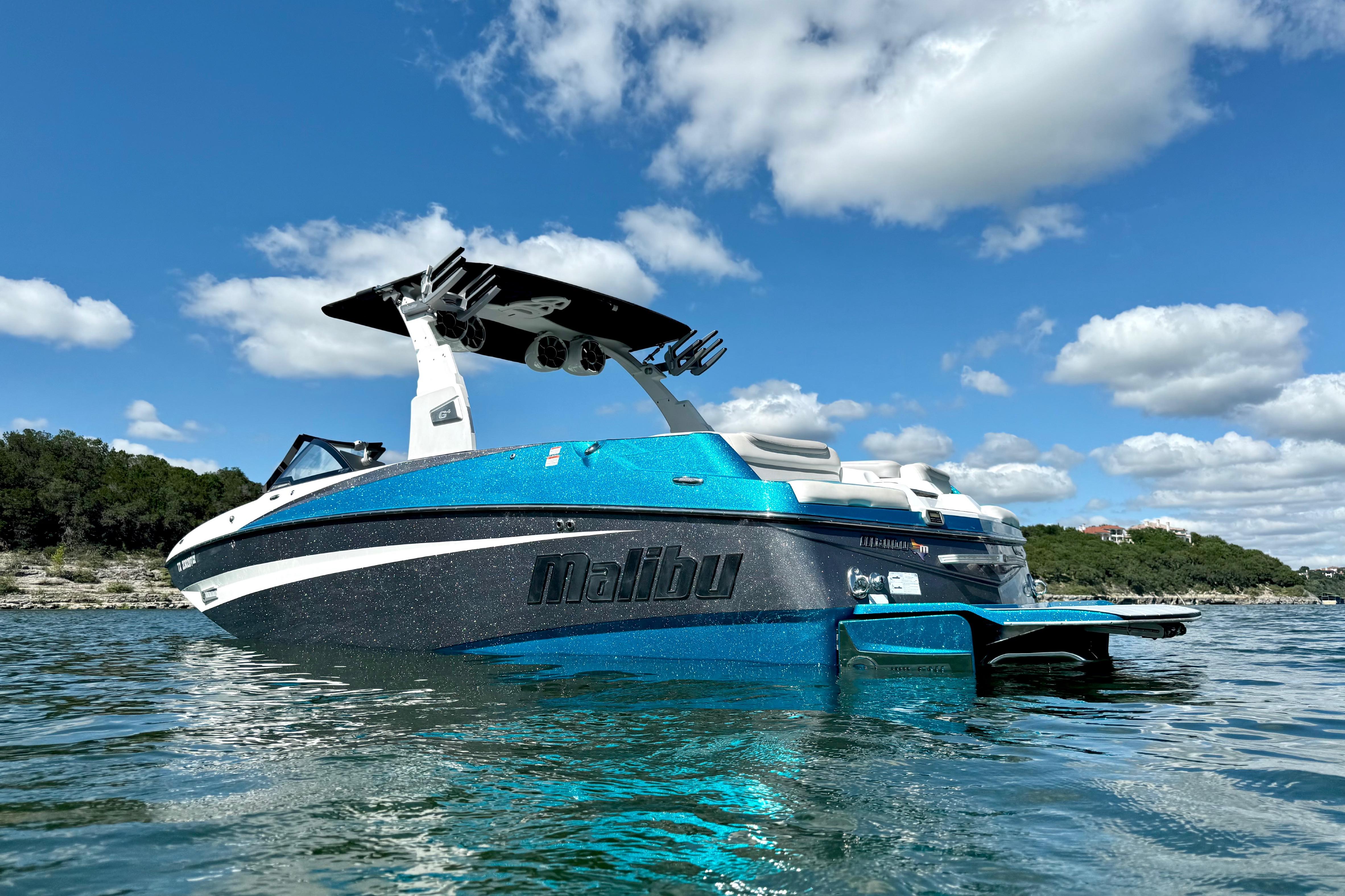 2017 Malibu M235 boat on water under blue sky with clouds.