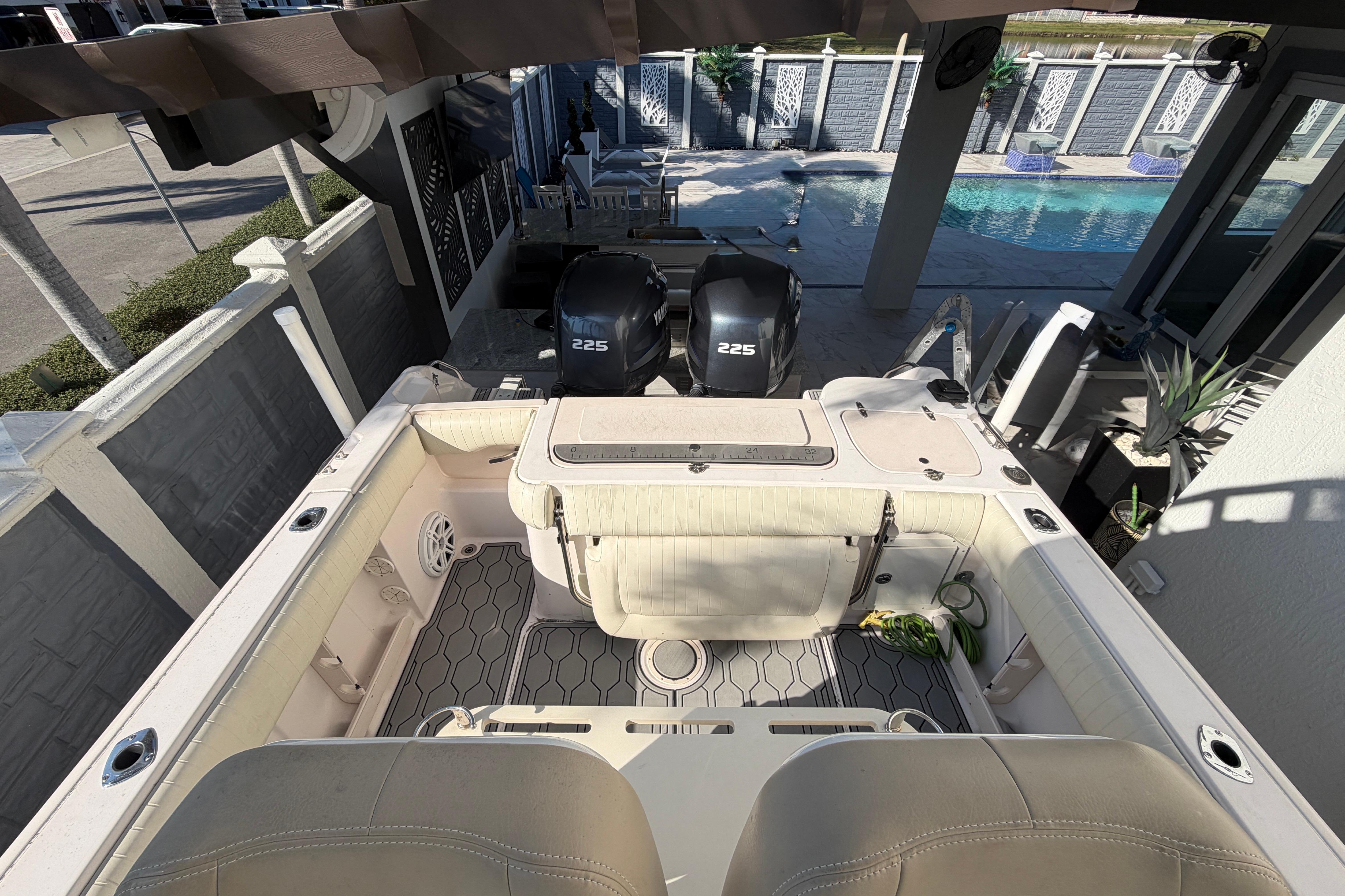 2004 Grady White 273 boat with twin 225 engines, docked near a poolside patio.