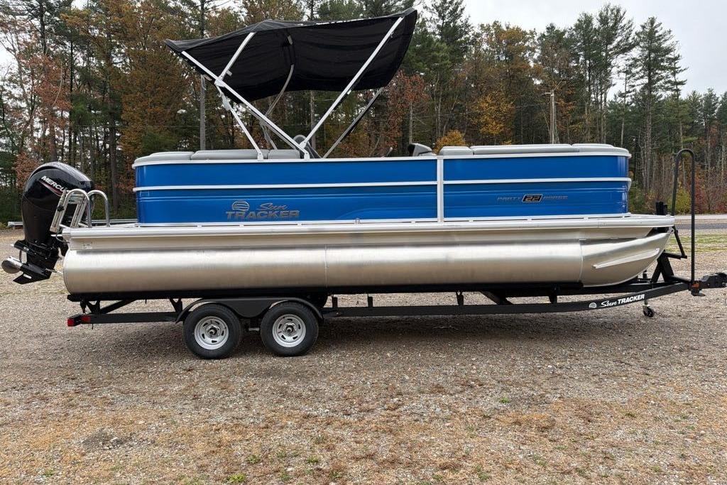 2026 Sun Tracker Party Barge 22 DLX pontoon boat on trailer, parked outdoors.