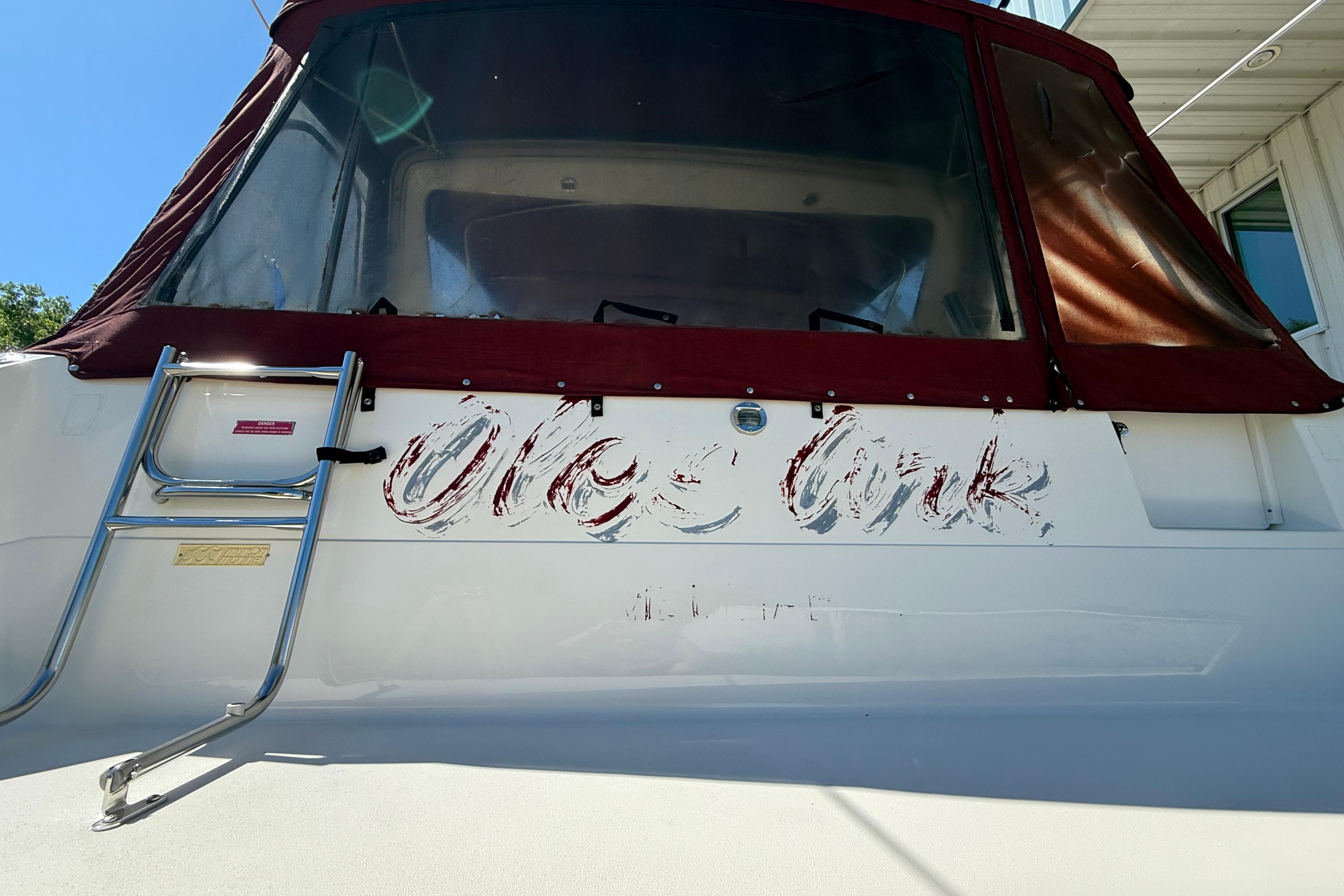 1990 Sea Ray 310 Express Cruiser with faded lettering and maroon canopy.