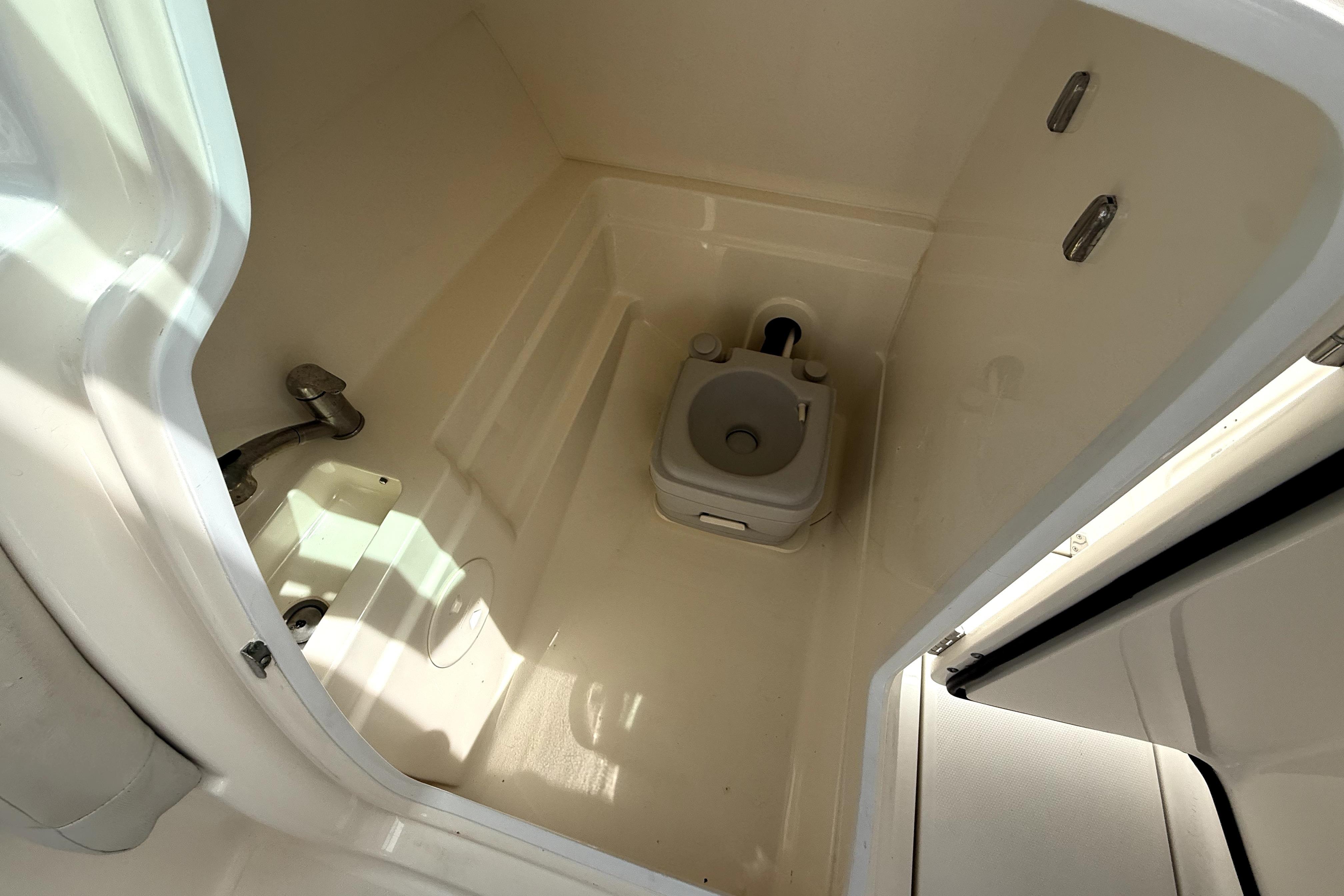 Interior of 2018 Boston Whaler 230 Vantage boat showing compact marine toilet.