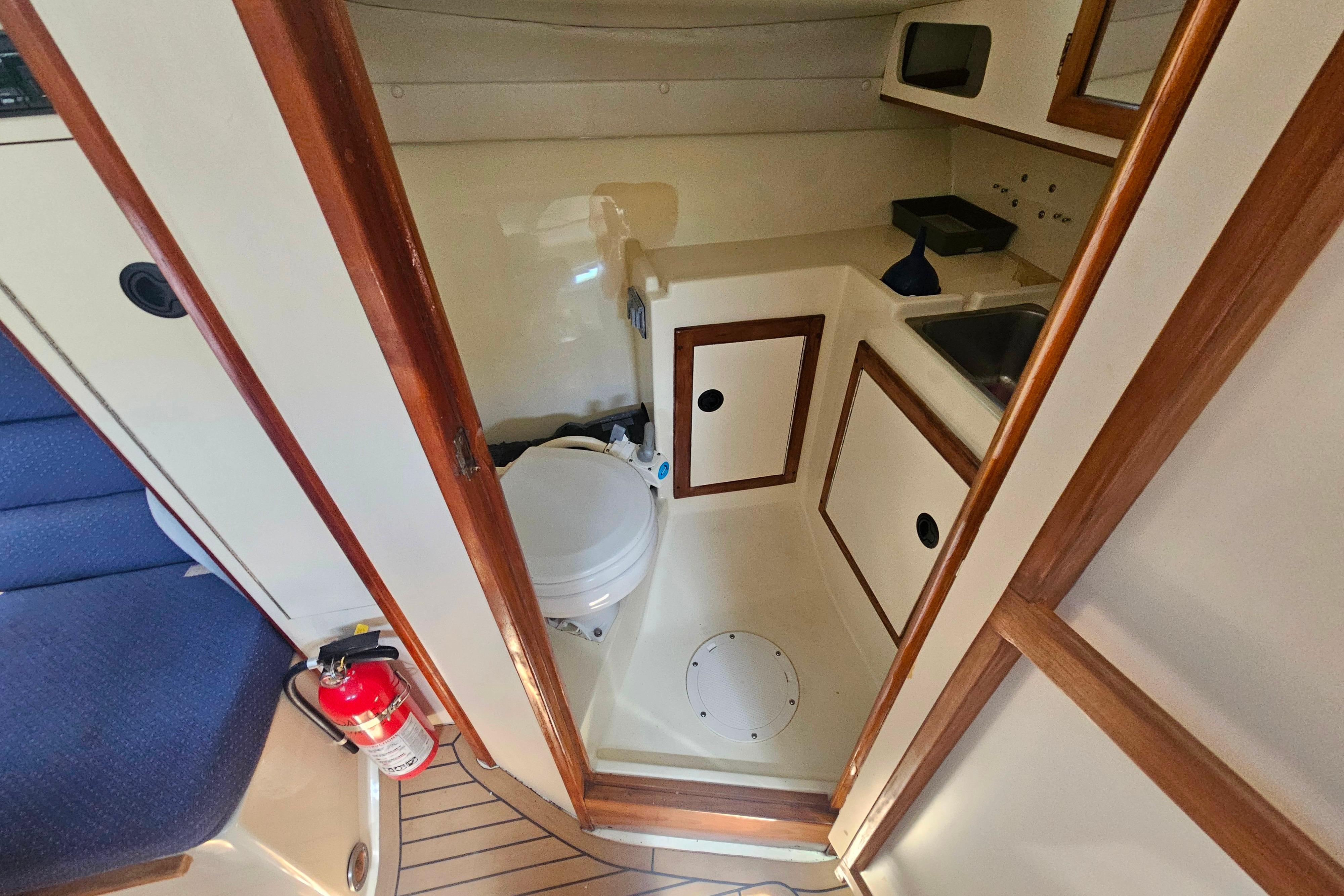 Interior of 1999 Albin 28 Tournament Express boat featuring compact bathroom and wooden accents.