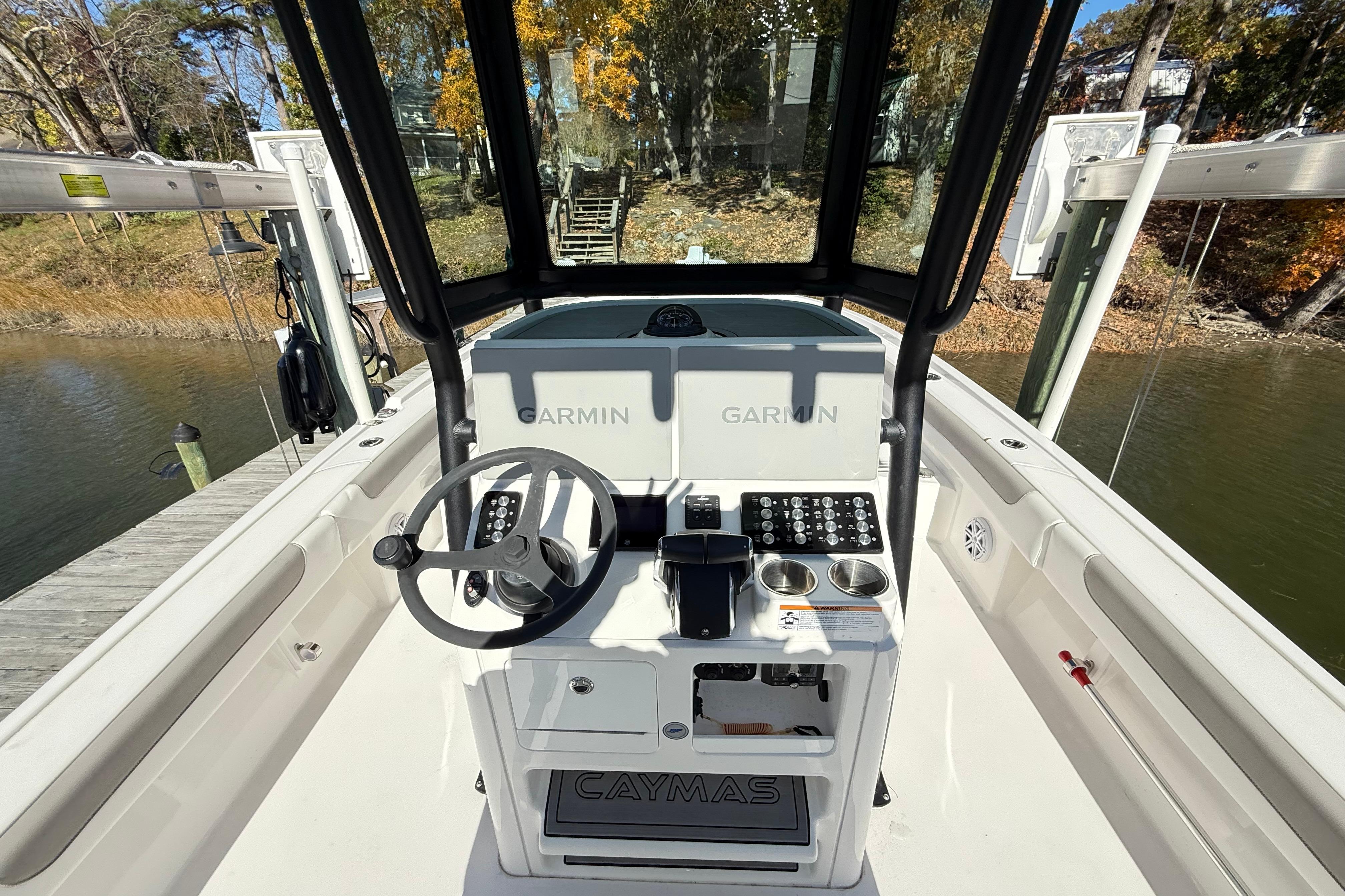 2023 Caymas 281 HB boat helm with Garmin electronics, docked by a scenic waterway.