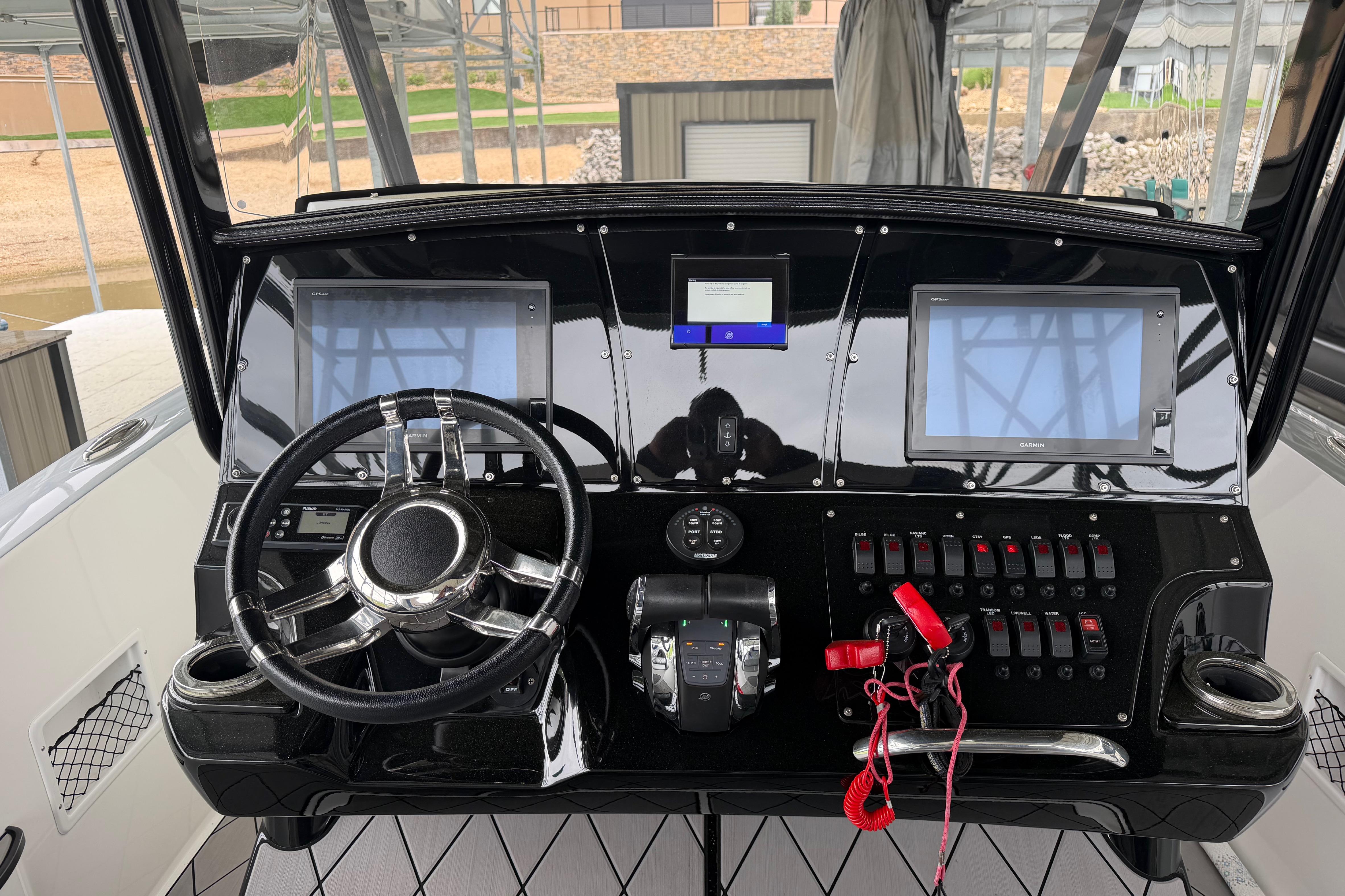 2018 Sunsation 32 CCX boat dashboard with steering wheel, dual screens, and control switches.