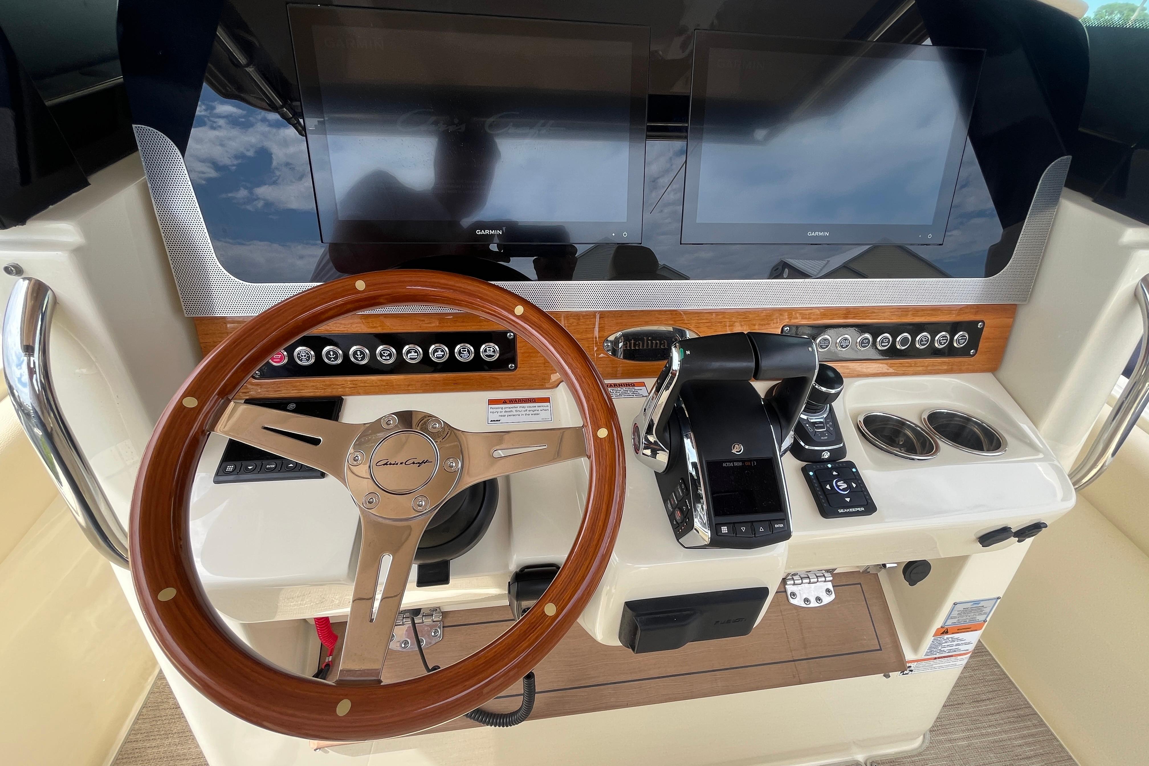 2024 Chris-Craft Catalina 30 helm with dual screens and wooden steering wheel.