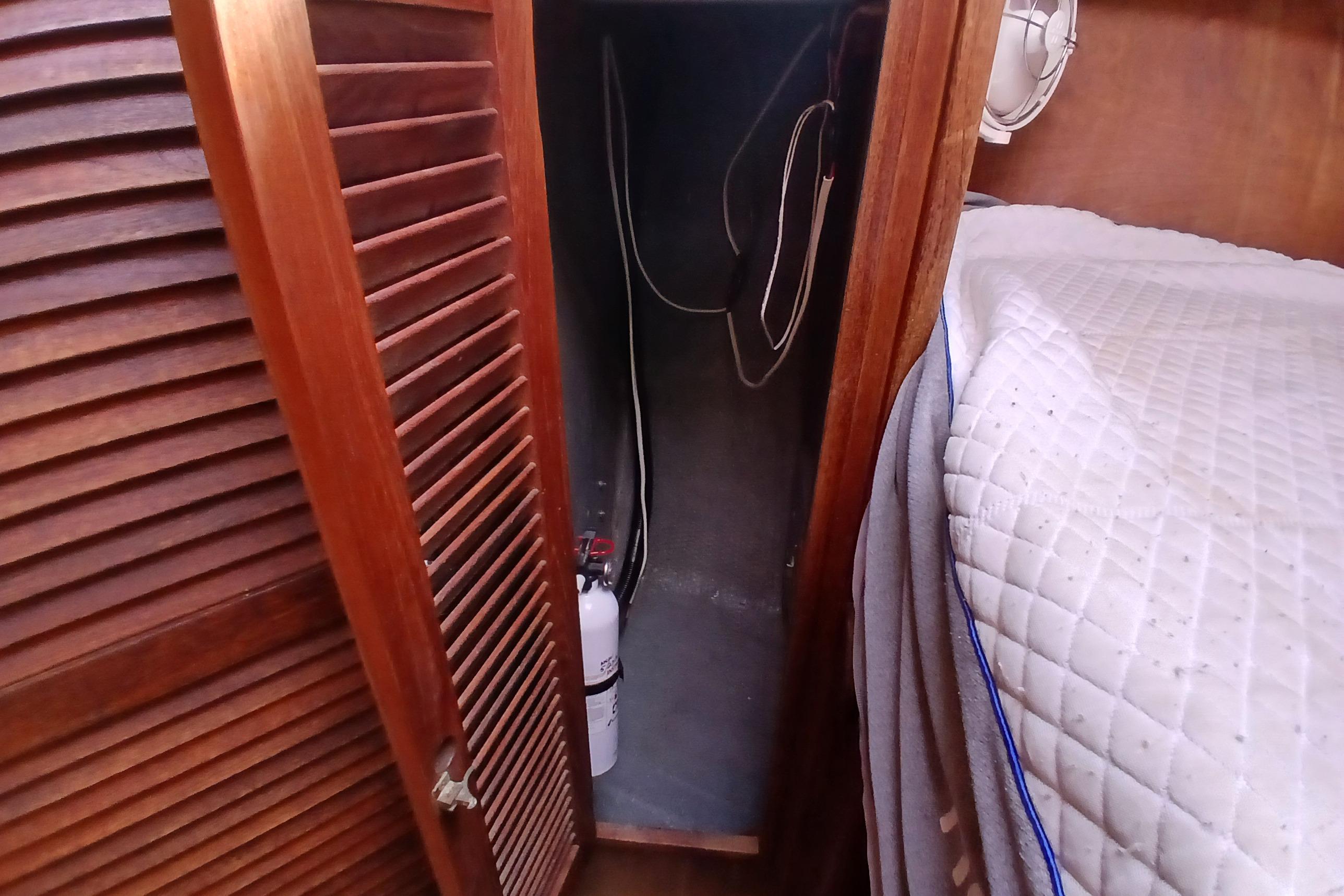 Wooden closet interior on a 1977 Tartan 37 sailboat, featuring a fire extinguisher.