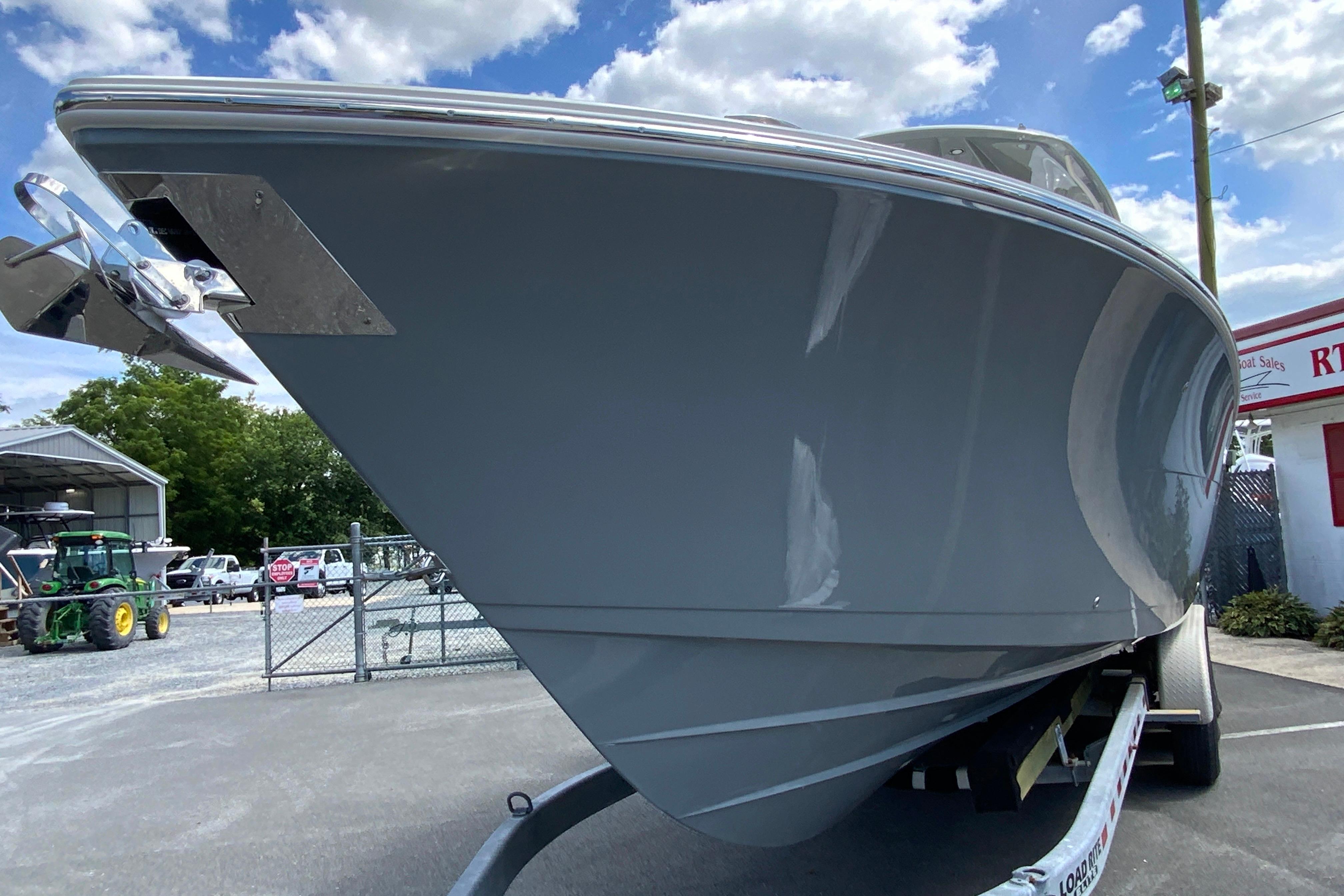 2027 Cobia 320 Center Console boat on trailer, viewed from the front under a blue sky.