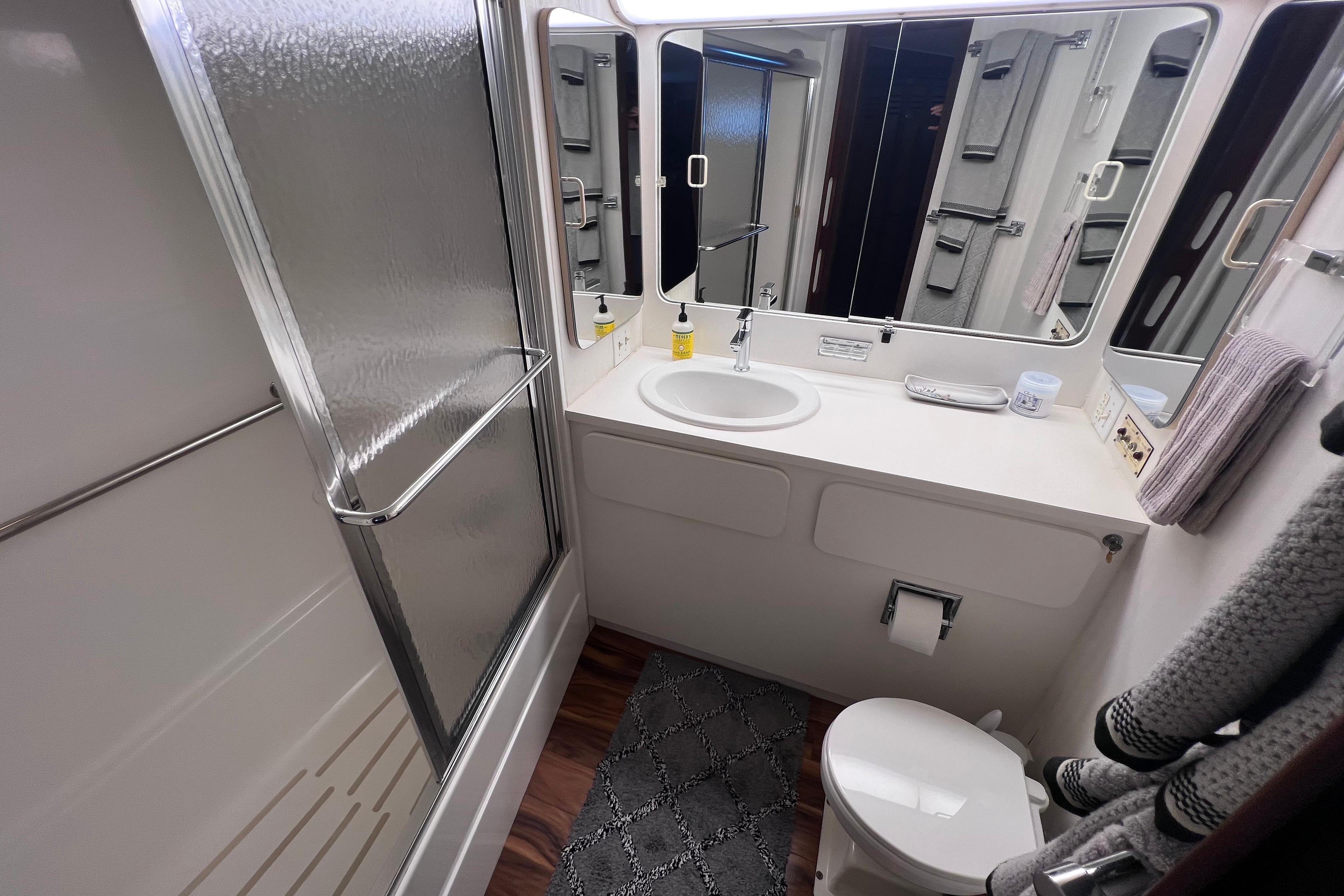 Bathroom interior of 1987 Hatteras 70 Cockpit Motor Yacht with shower, sink, and toilet.
