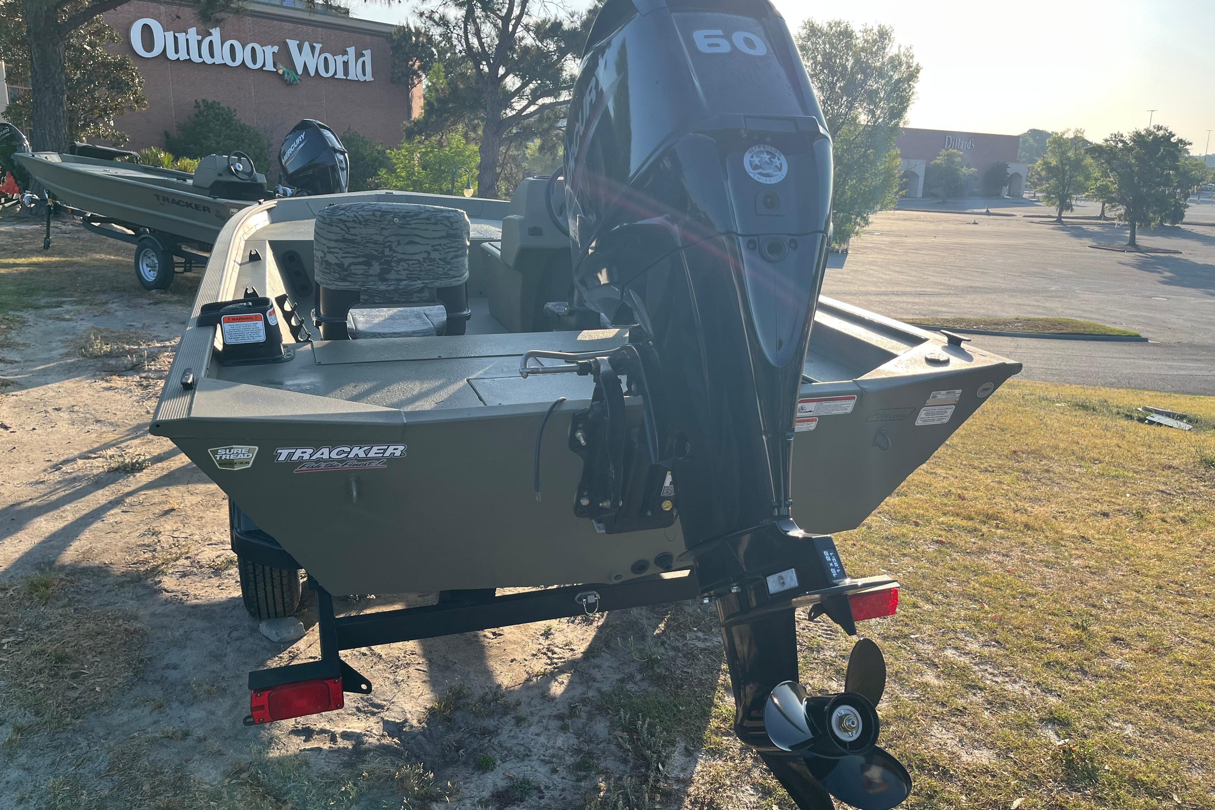 2026 Tracker Grizzly 1754 SC boat with motor, parked near Outdoor World store.