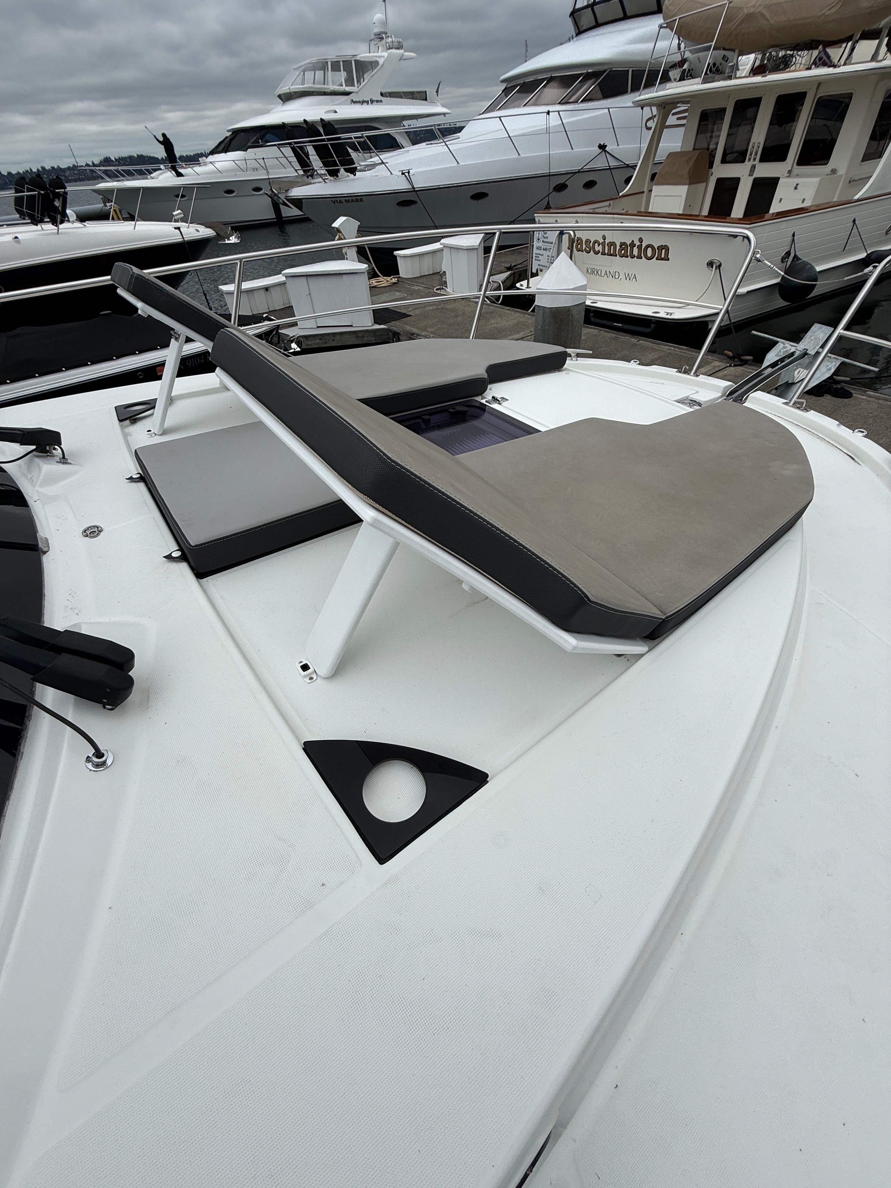 A sun deck on a 2021 Jeanneau NC 1095, surrounded by other boats in the harbor.