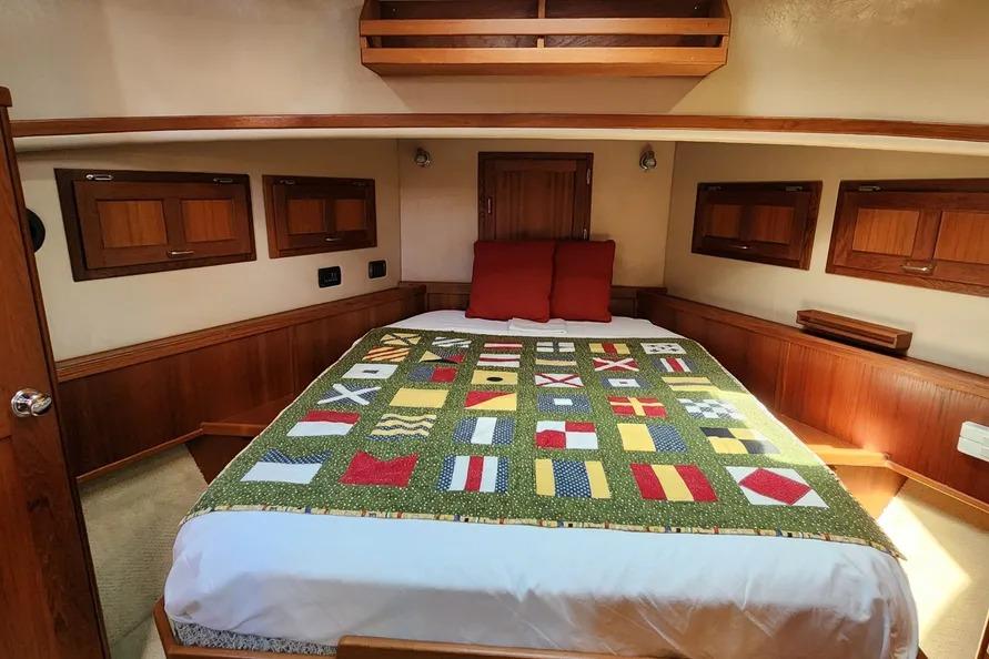Cozy cabin interior of 2006 American Tug AT with nautical-themed bedding and wooden accents.