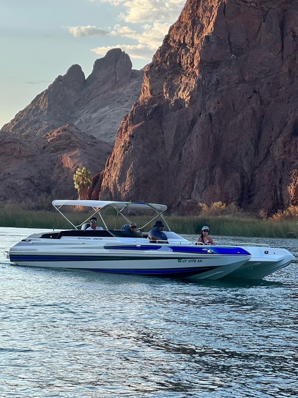 Custom Barron 290s boat 2021 on a serene lake with rocky backdrop.