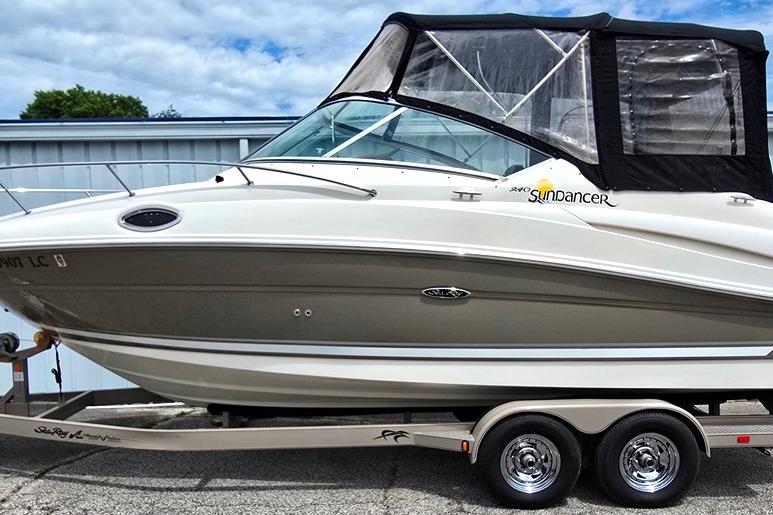 2006 Sea Ray 240 Sundancer boat on trailer, featuring sleek design and protective canopy.