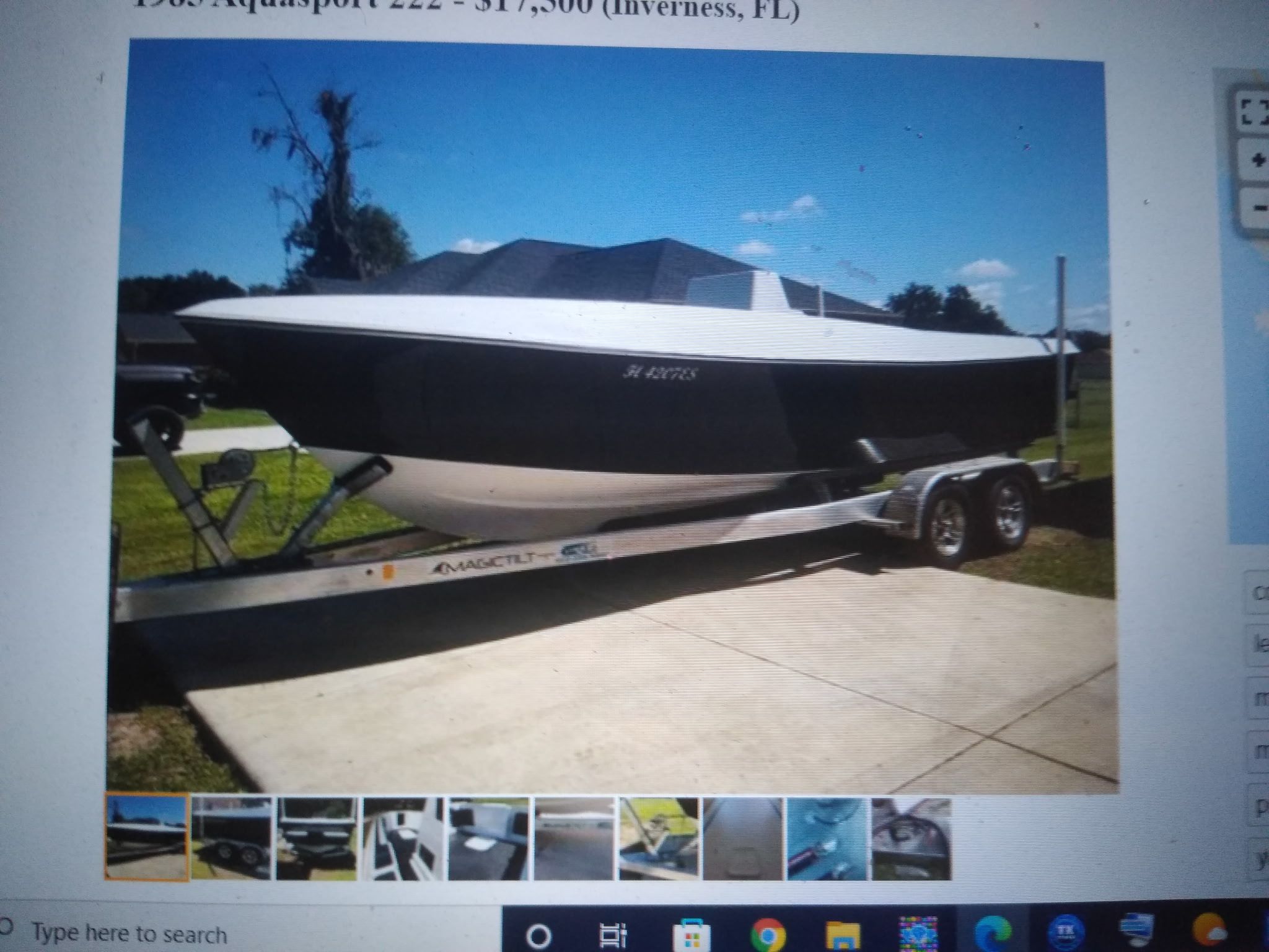 An Aquasport boat on a trailer, parked on a driveway.